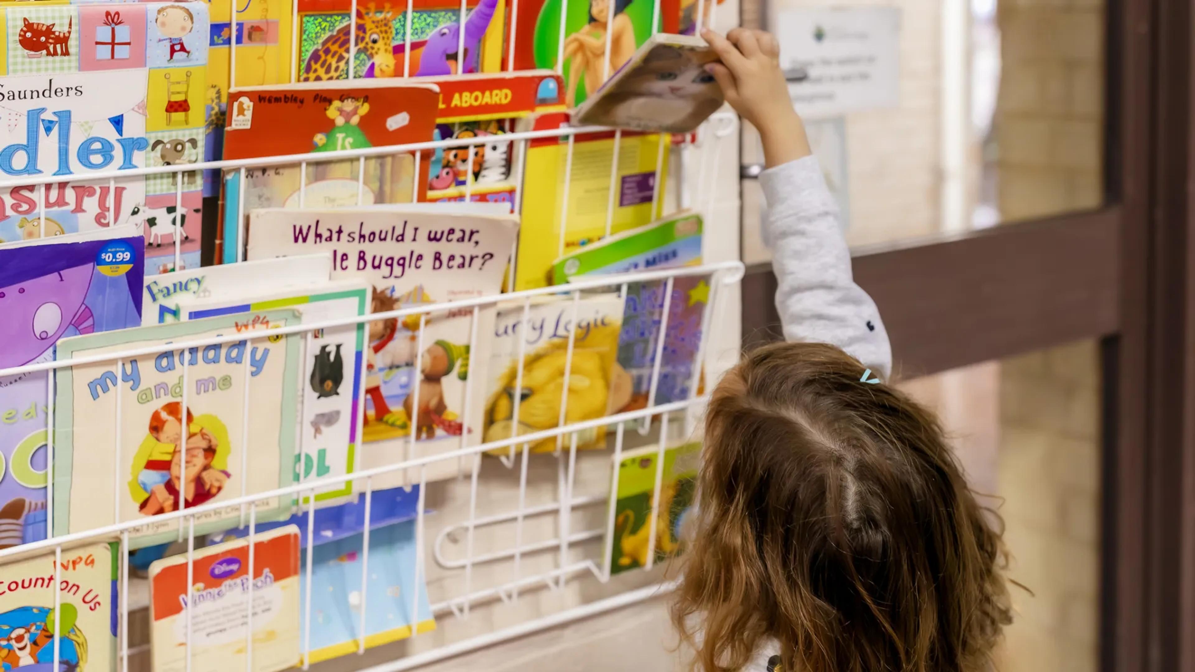 A photo of a little girl grabbing a book.