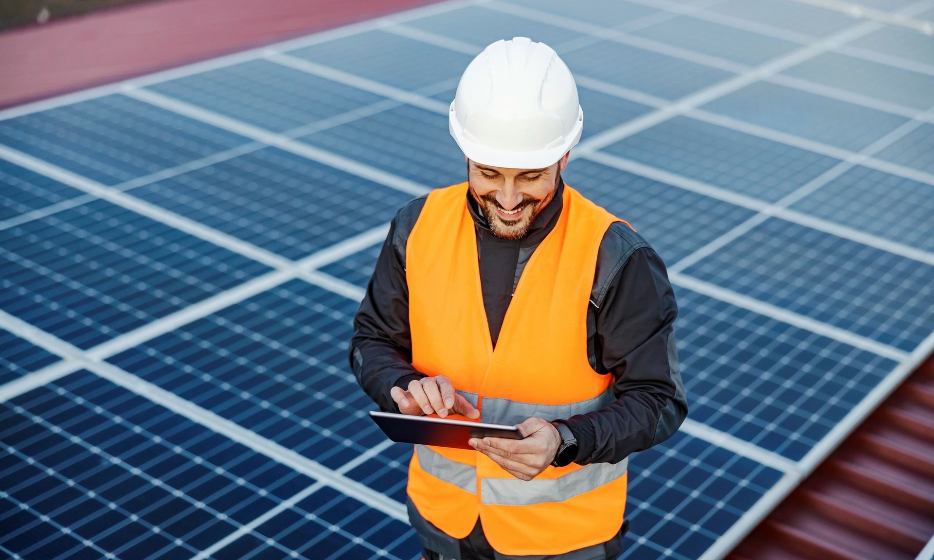 man in orange vest maintaing solar panels