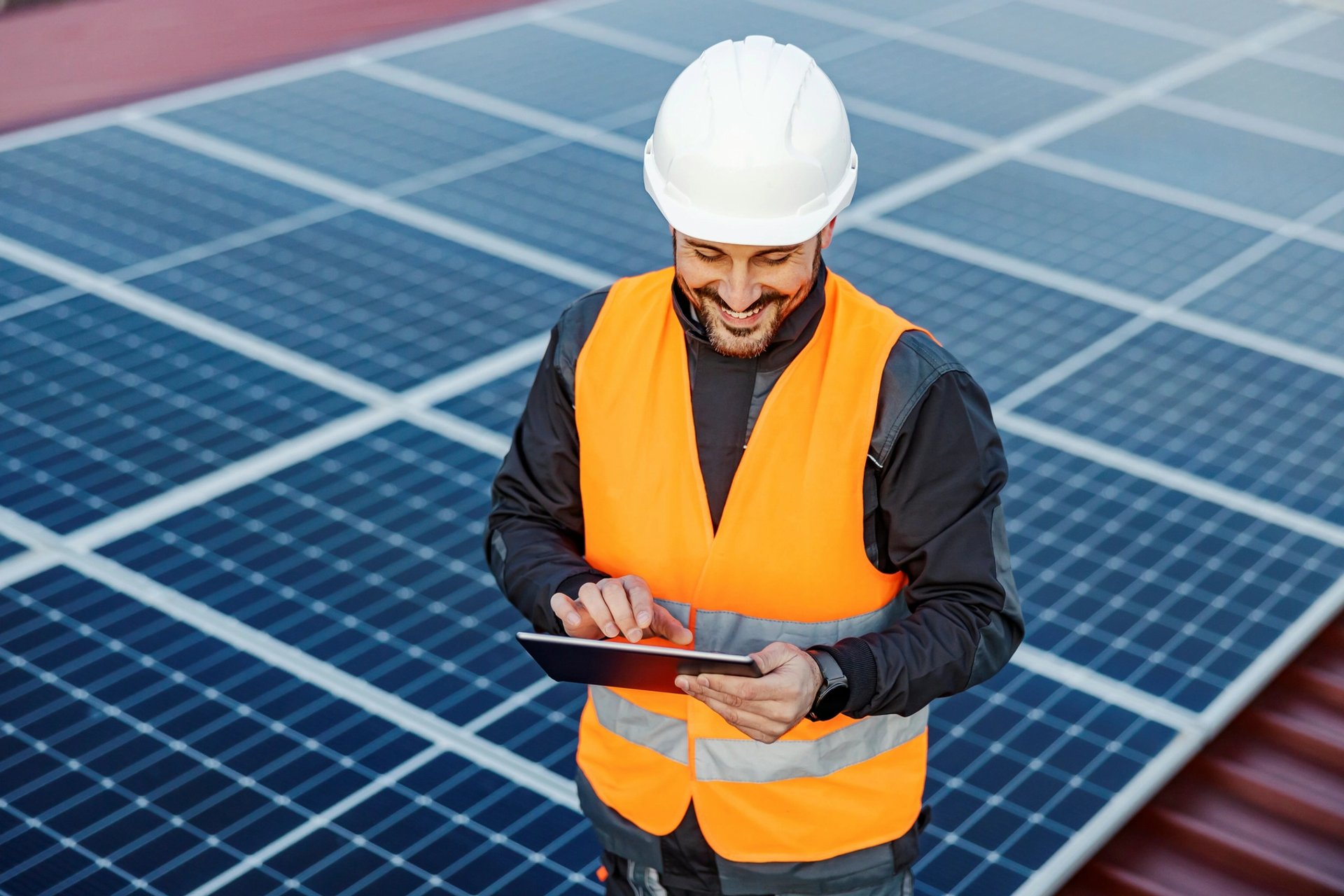 man in orange vest maintaining solar panels