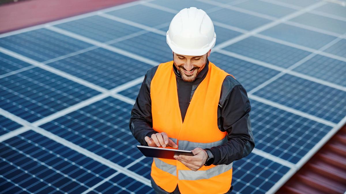 man in orange vest maintaing solar panels