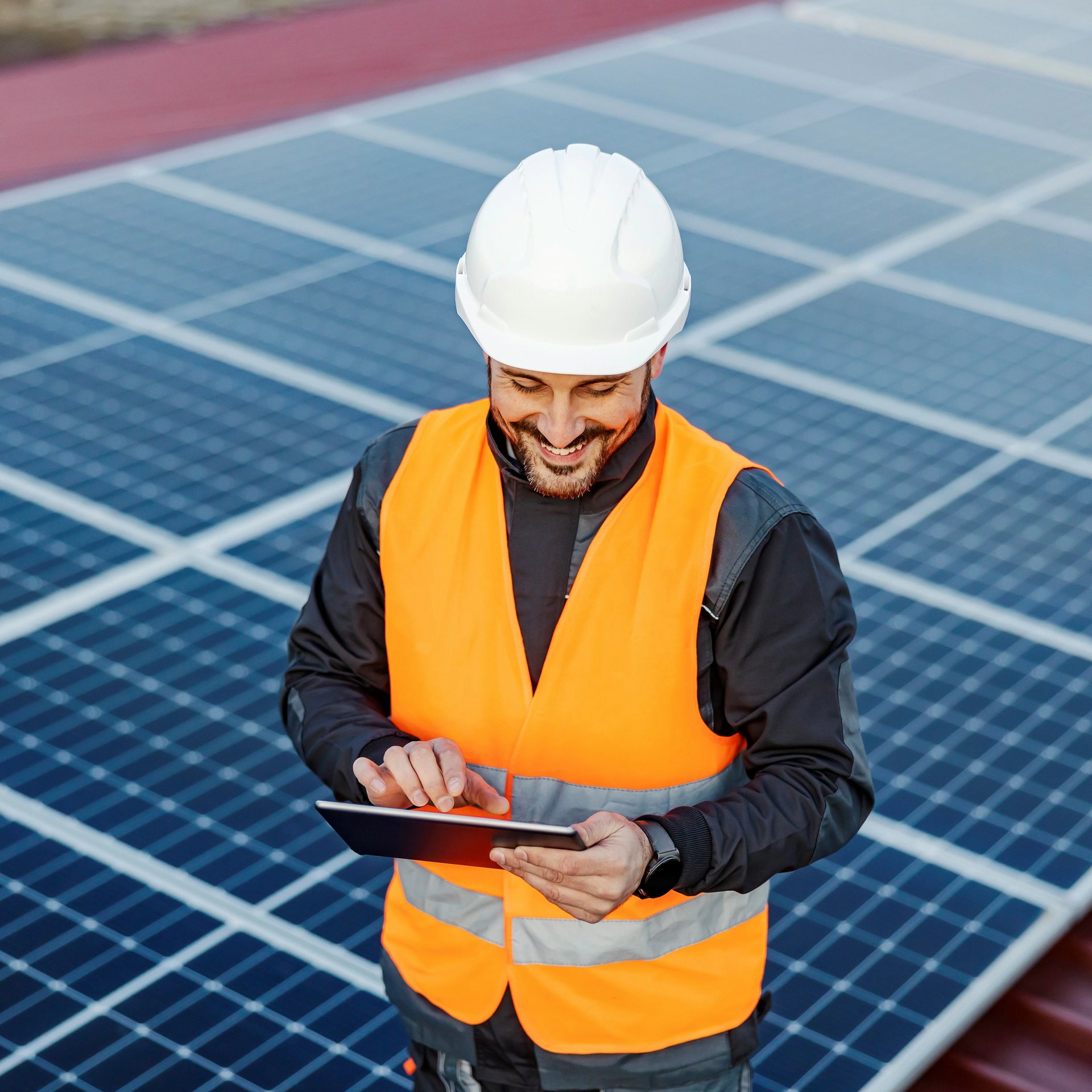 man in orange vest maintaing solar panels