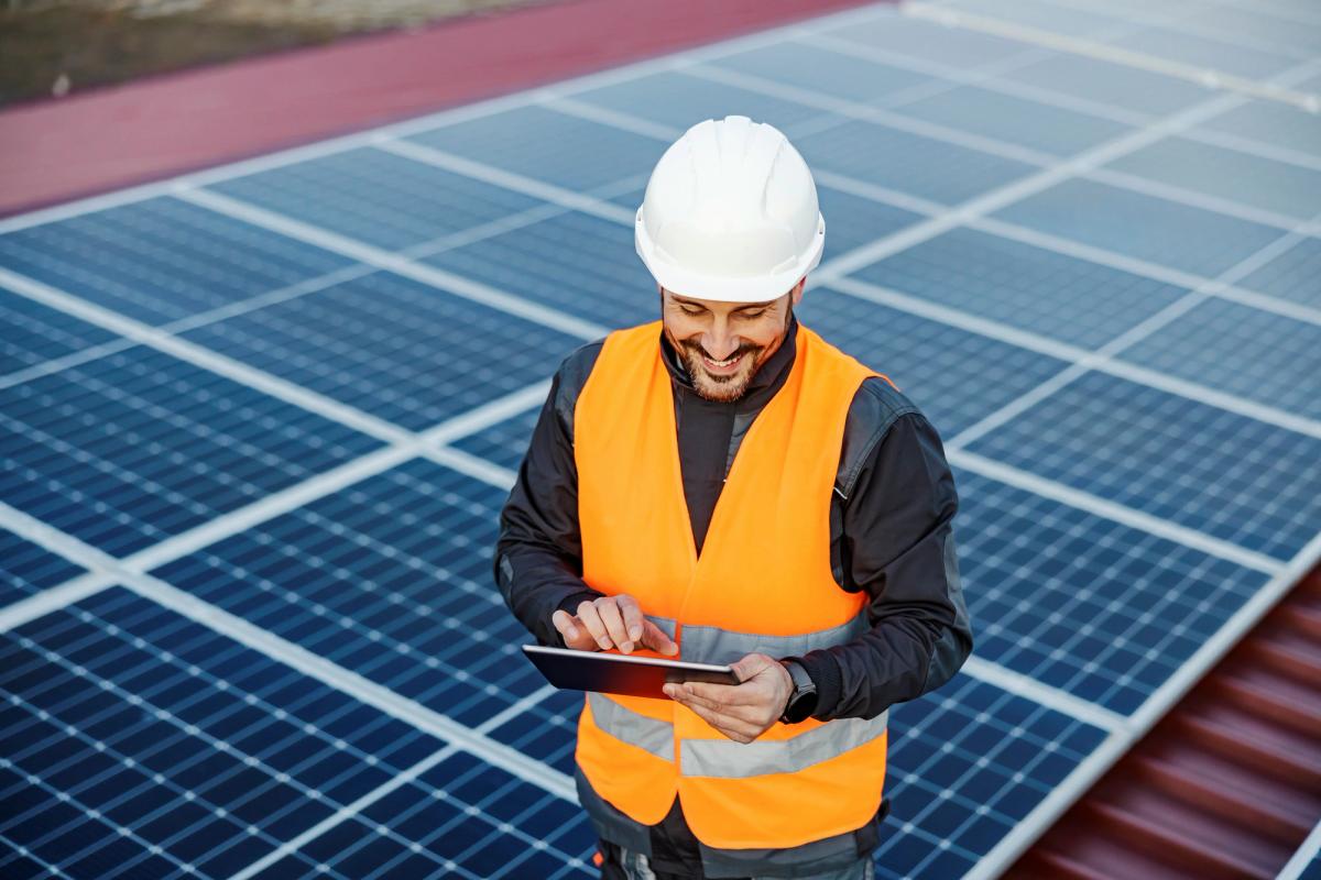 man in orange vest maintaining solar panels