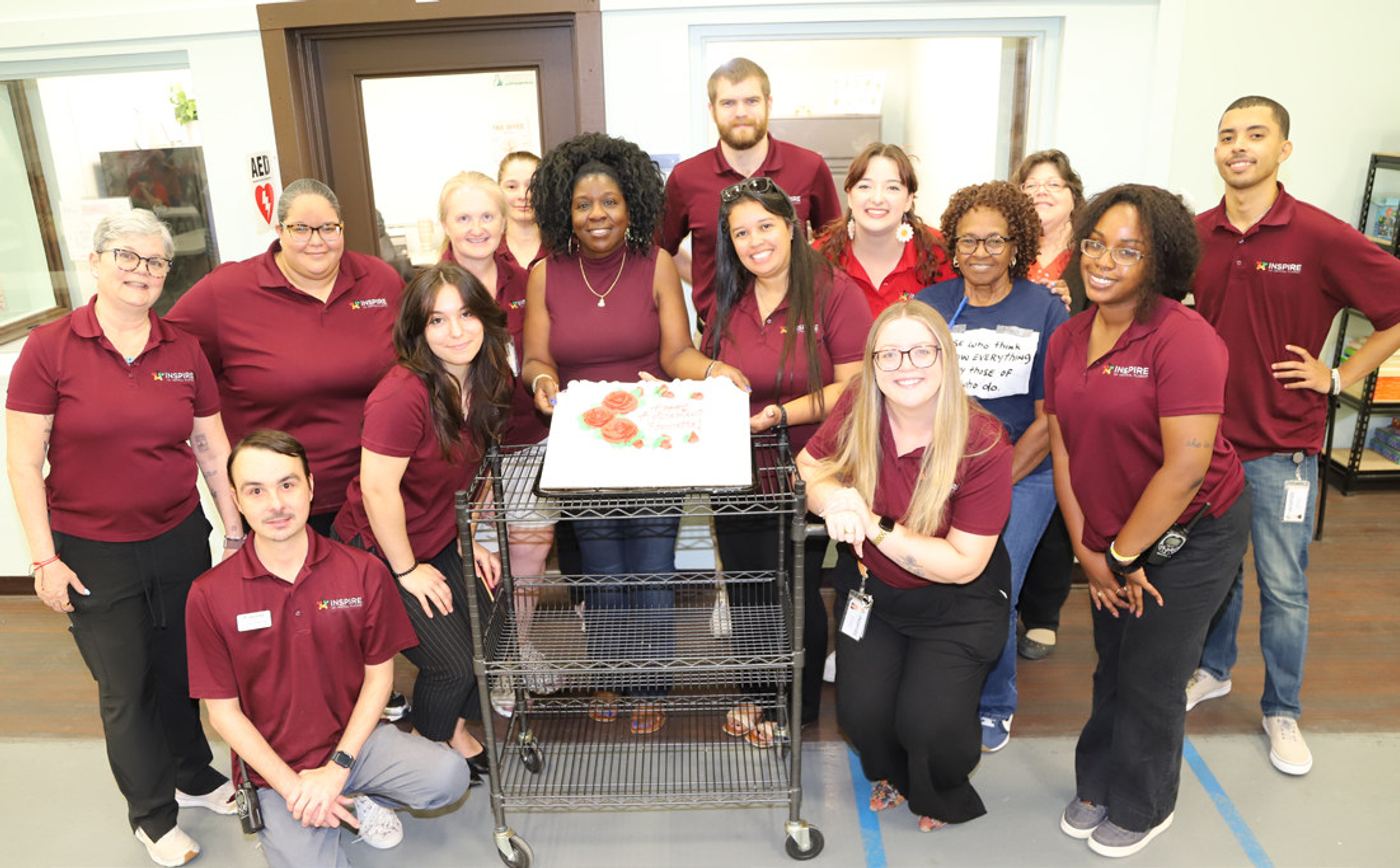Harrette Thompson (center, holding cake), surrounded by Inspire teammates at her retirement party