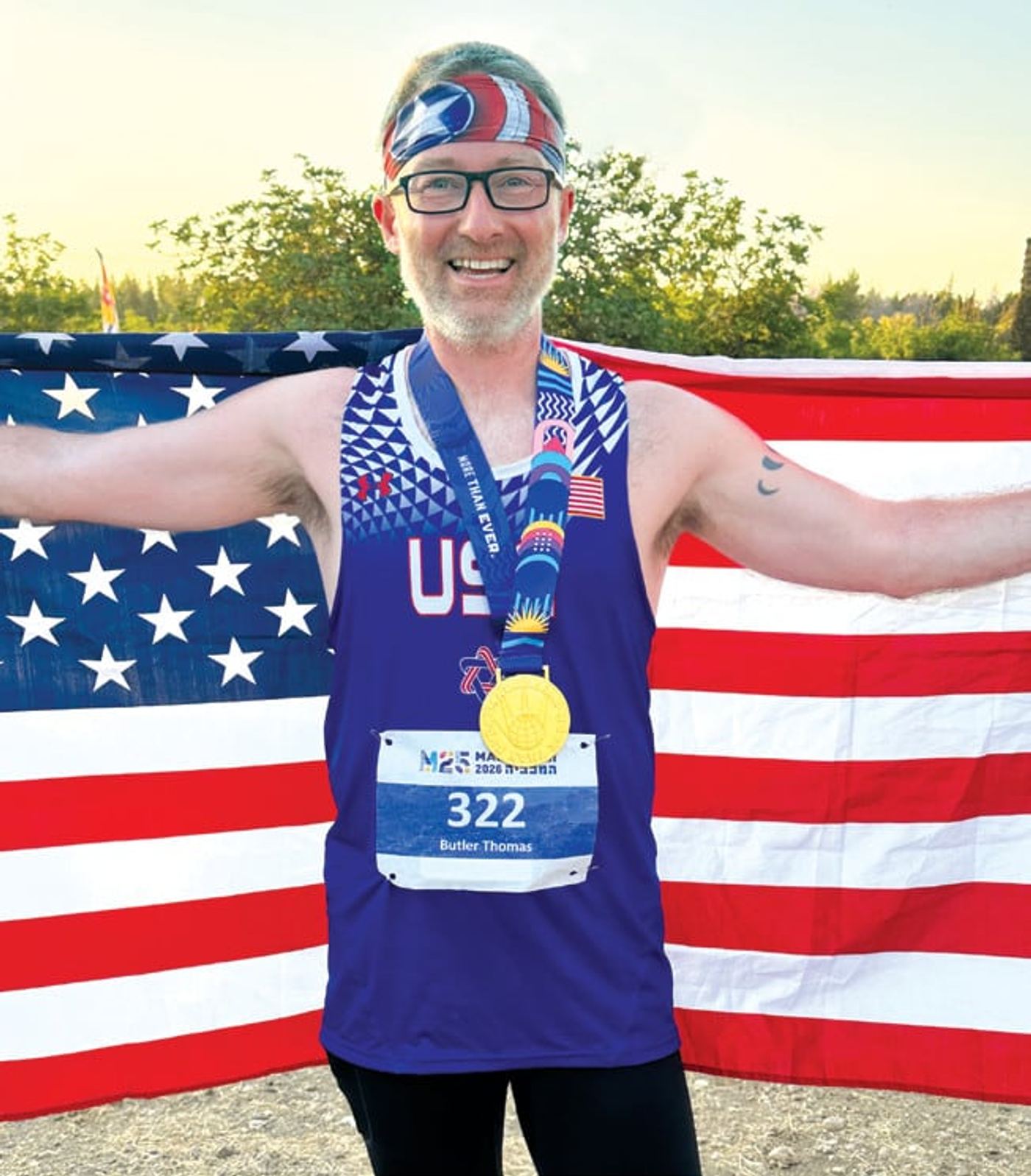 Tom Butler holds an American flag and wears his Maccabiah Games gold medal