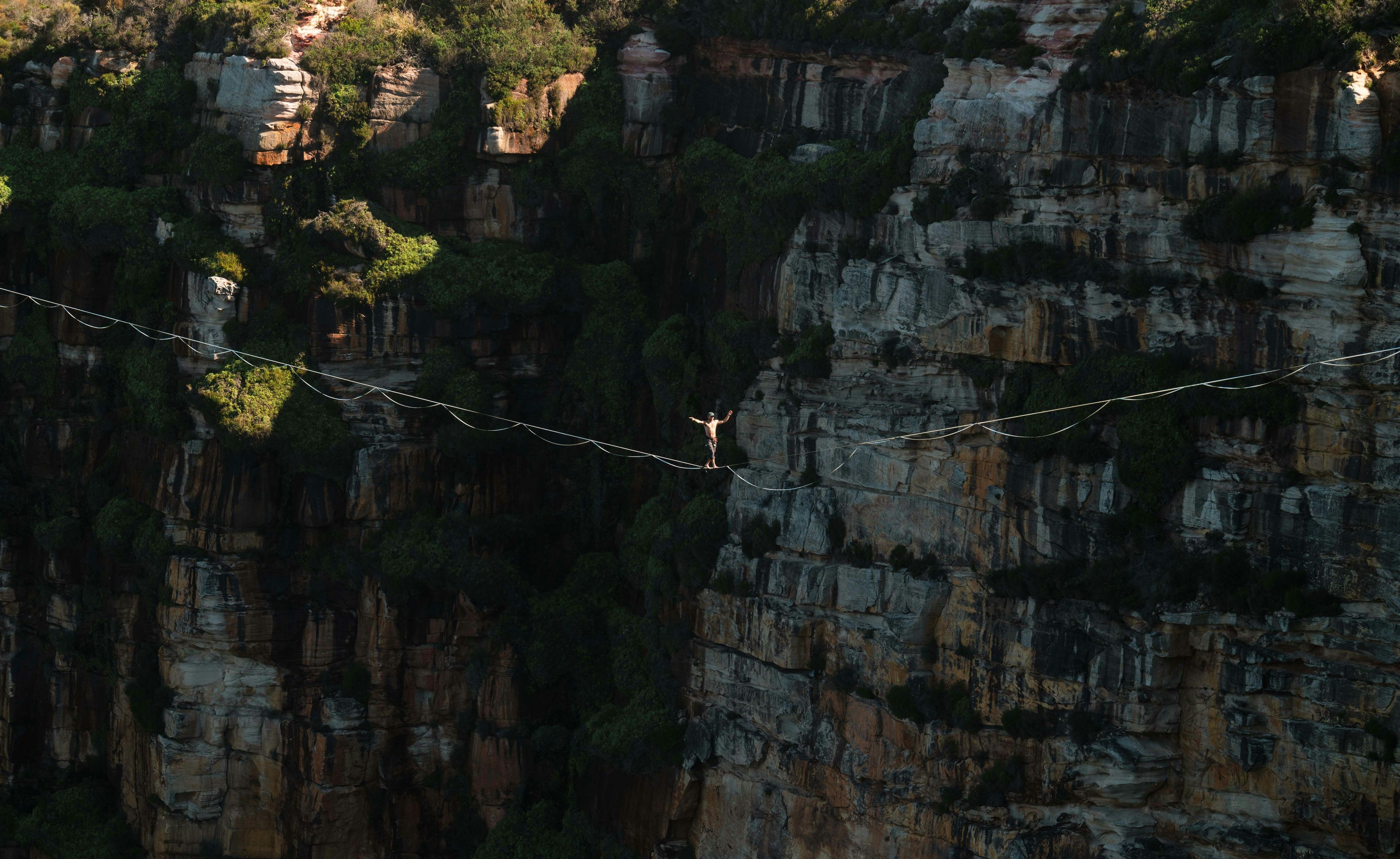 Person standing on a rope between mountains demonstrating risk