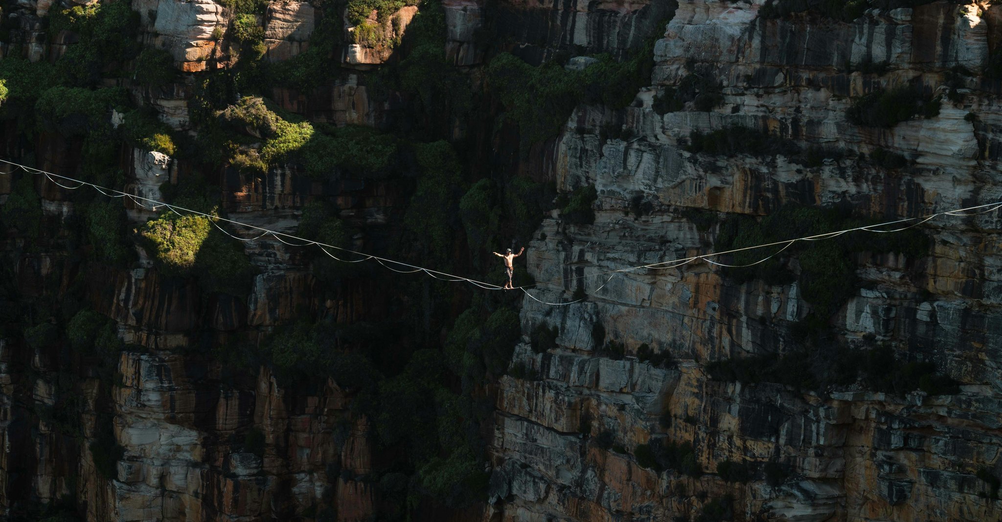 Person standing on a rope between mountains demonstrating risk