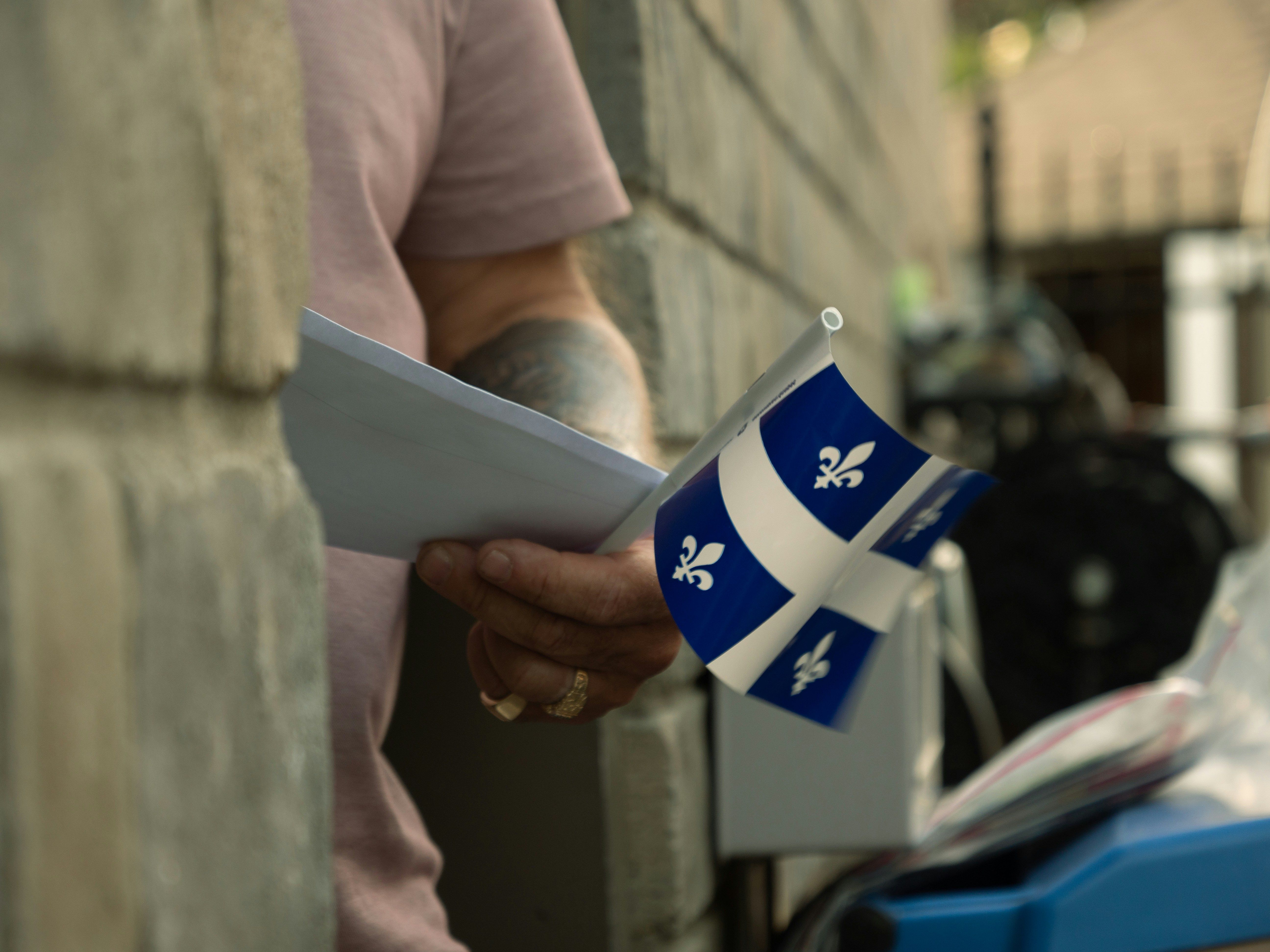 Man holding papers and a flag of Quebec