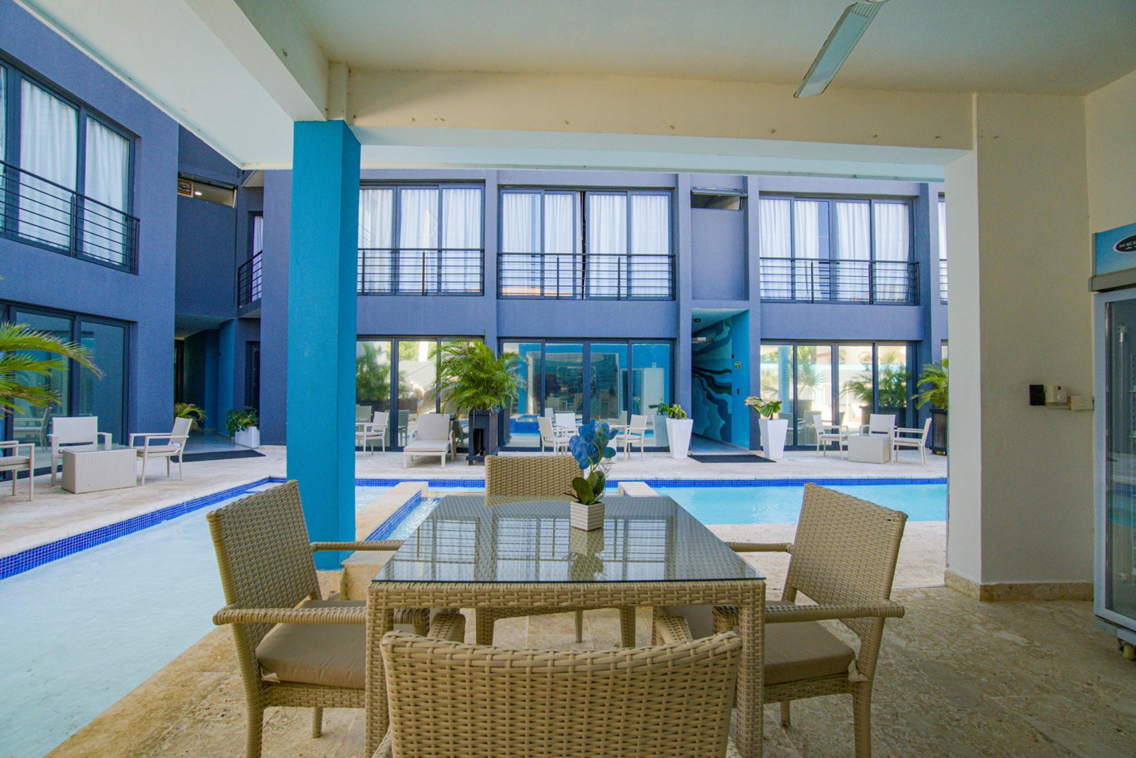 A dining table and wicker chairs in the shaded poolside lounge