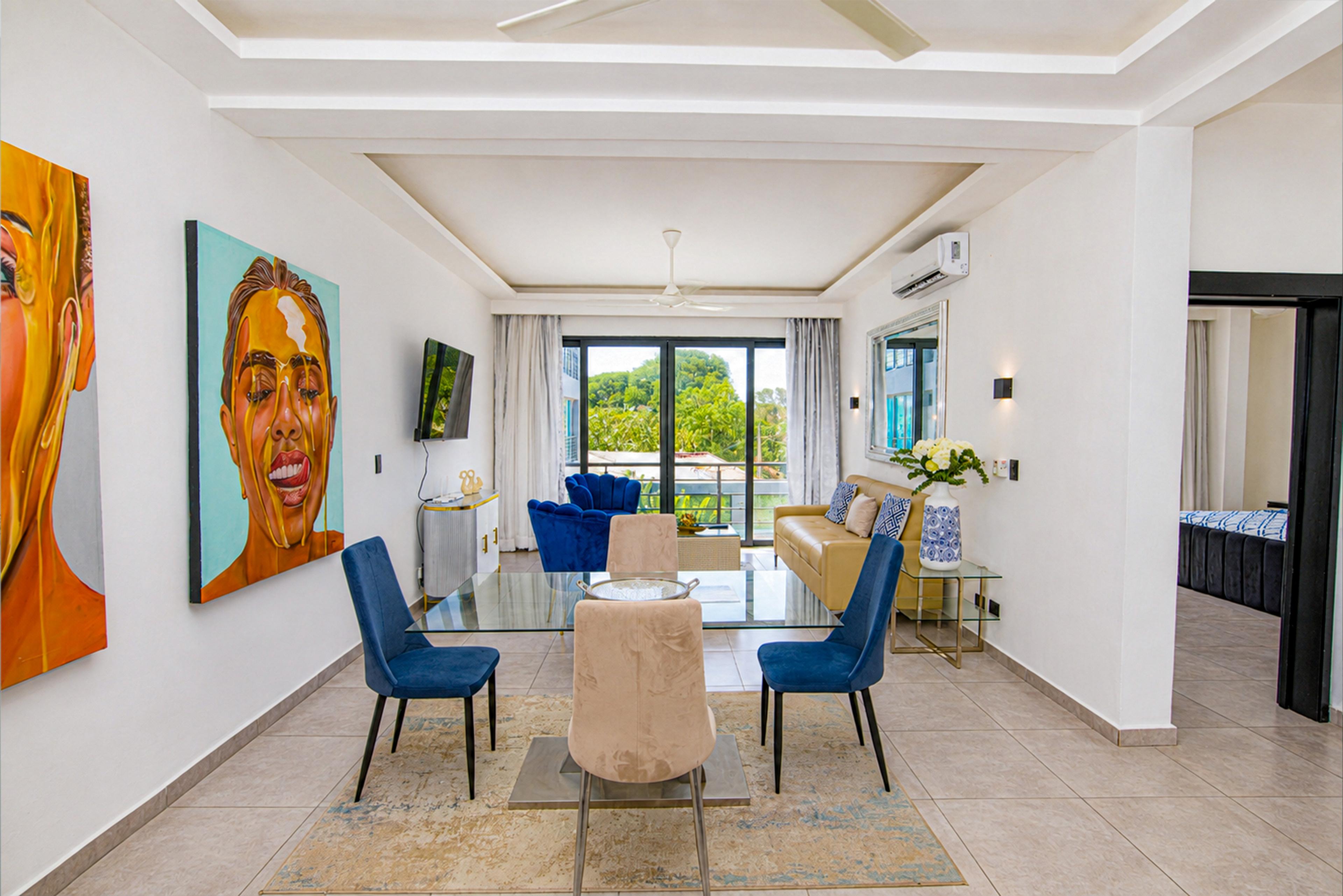 Dining area with blue chairs beneath two portrait murals