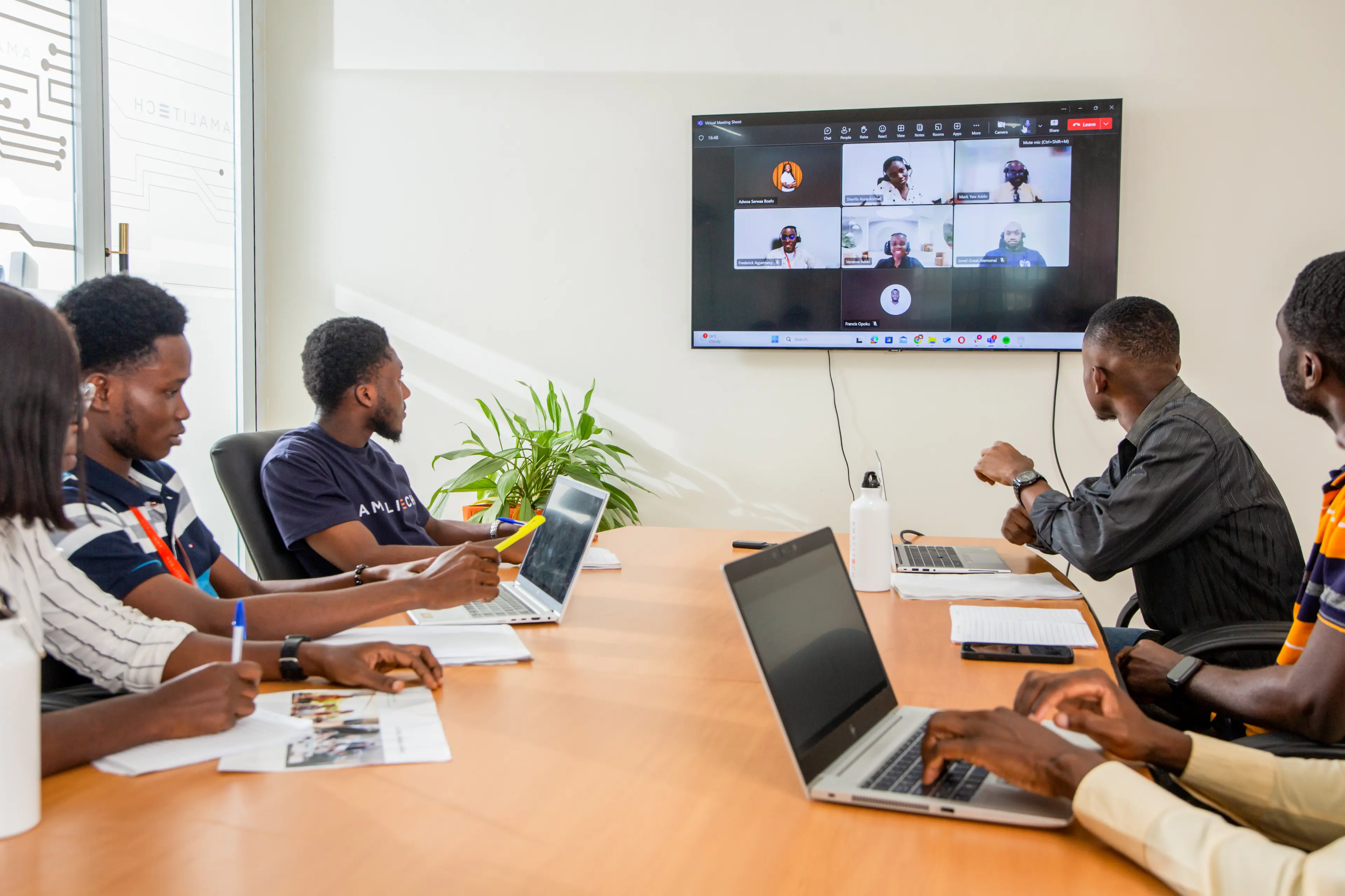 A team gathered around a conference table, taking part in a virtual meeting