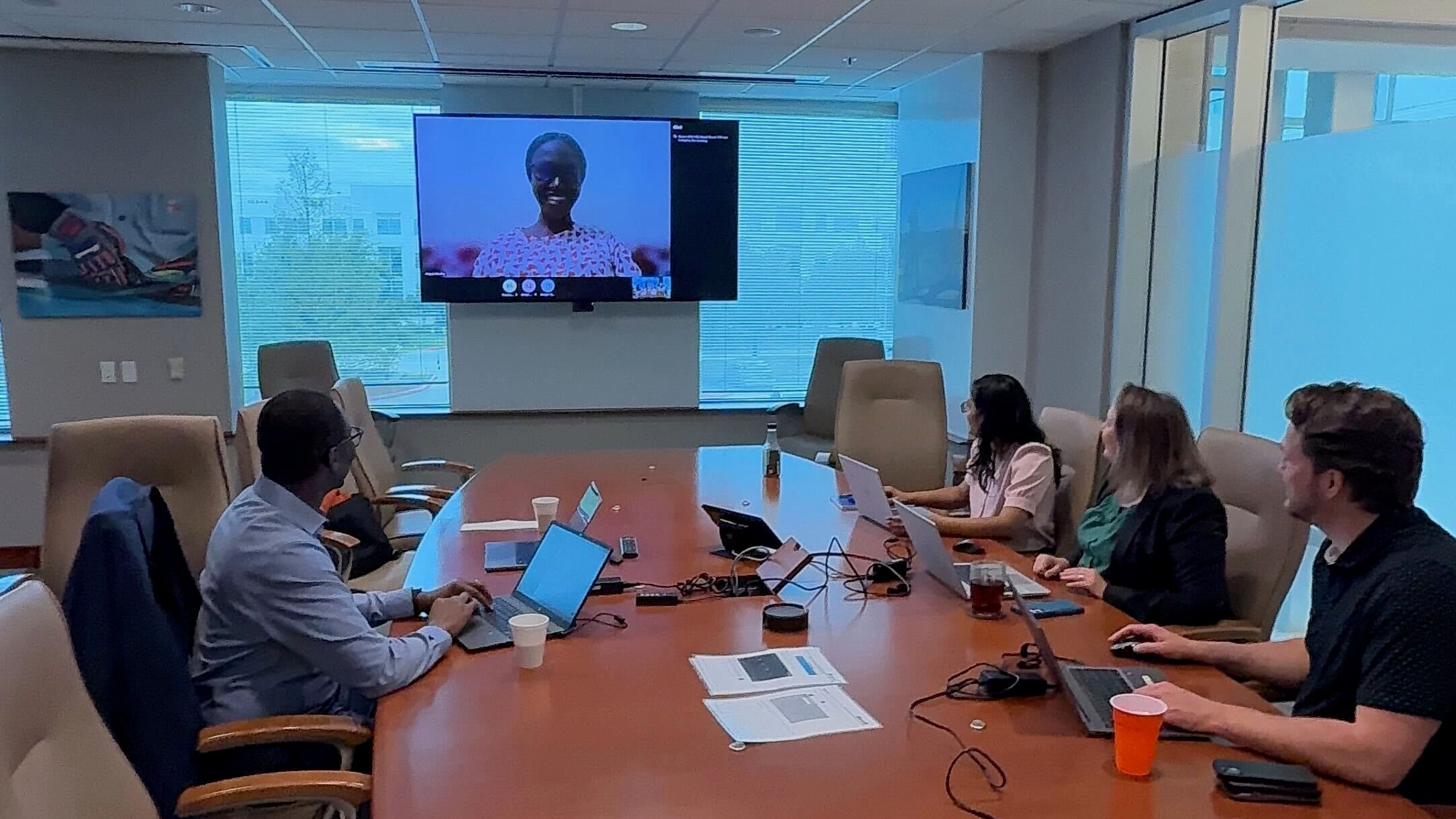 A group taking part in a virtual meeting, while seated at a conference table