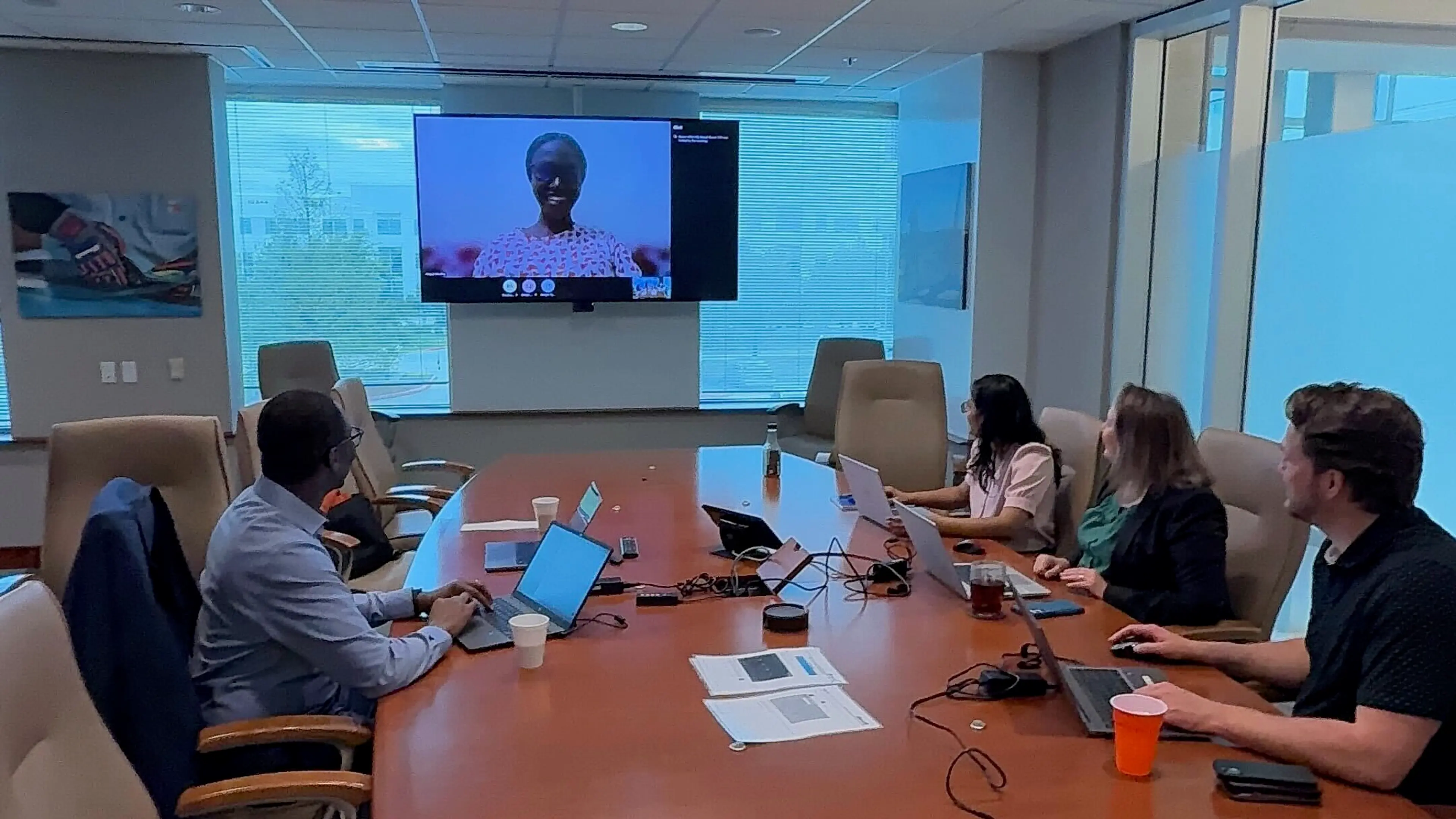 A group taking part in a virtual meeting, while seated at a conference table