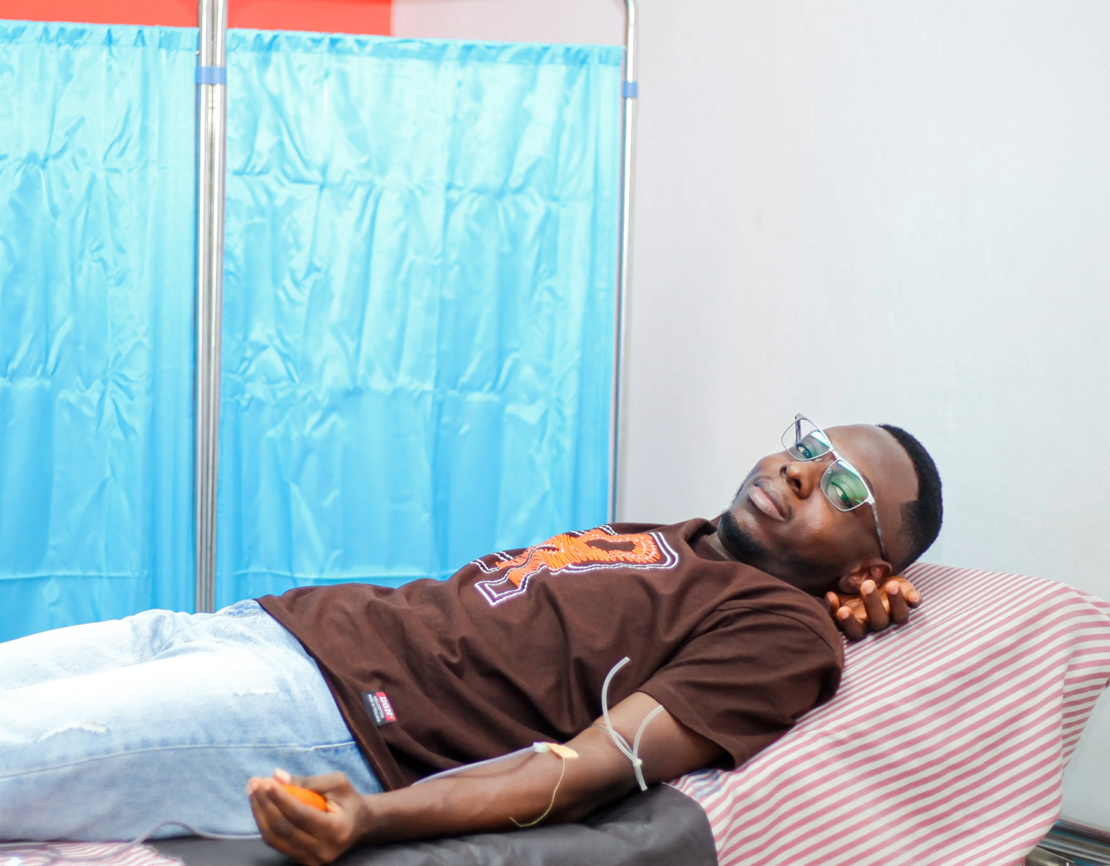 a guy lying on a hospital bed being attended to by a nurse