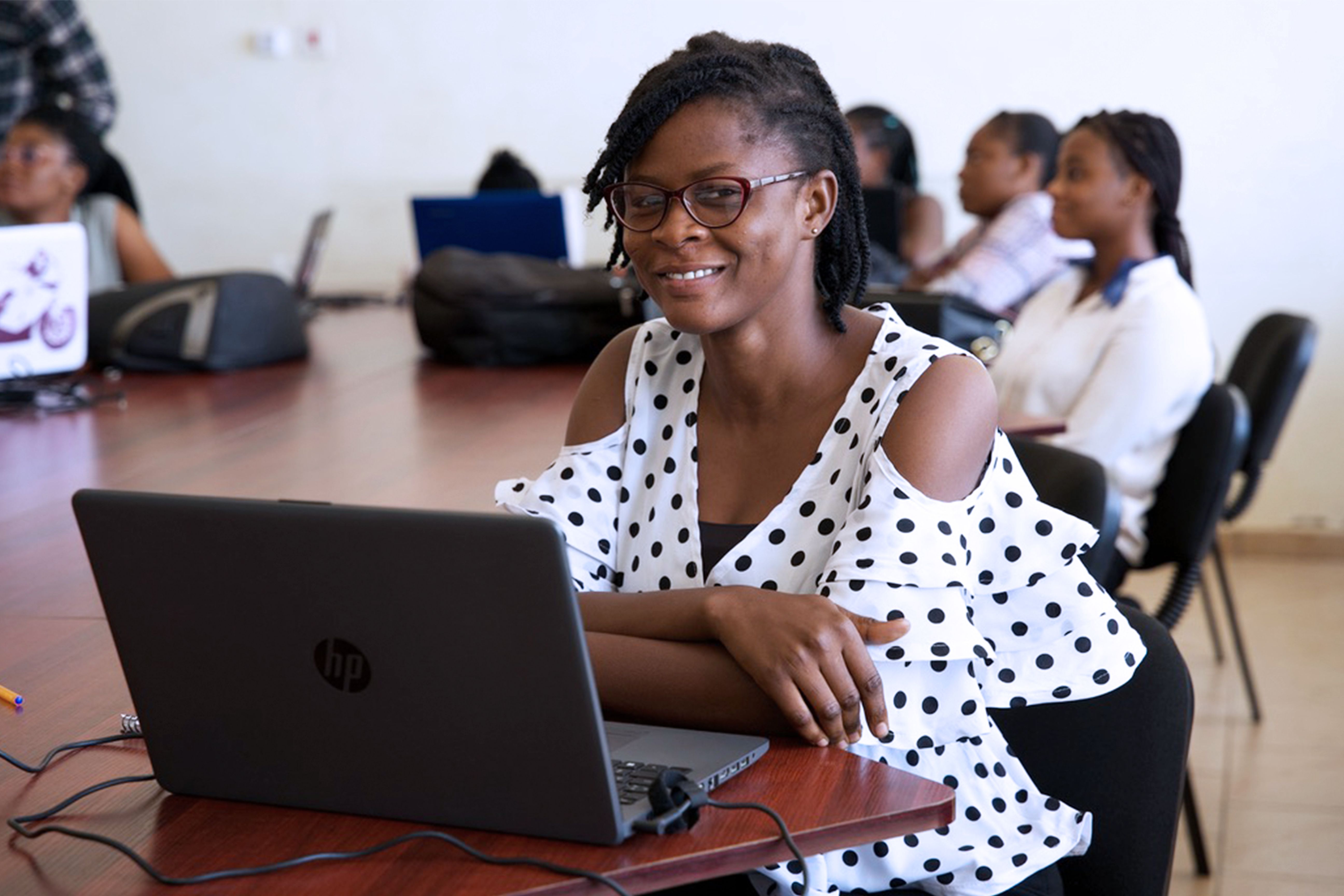 African woman using a laptop during a technology training session with other participants in the background