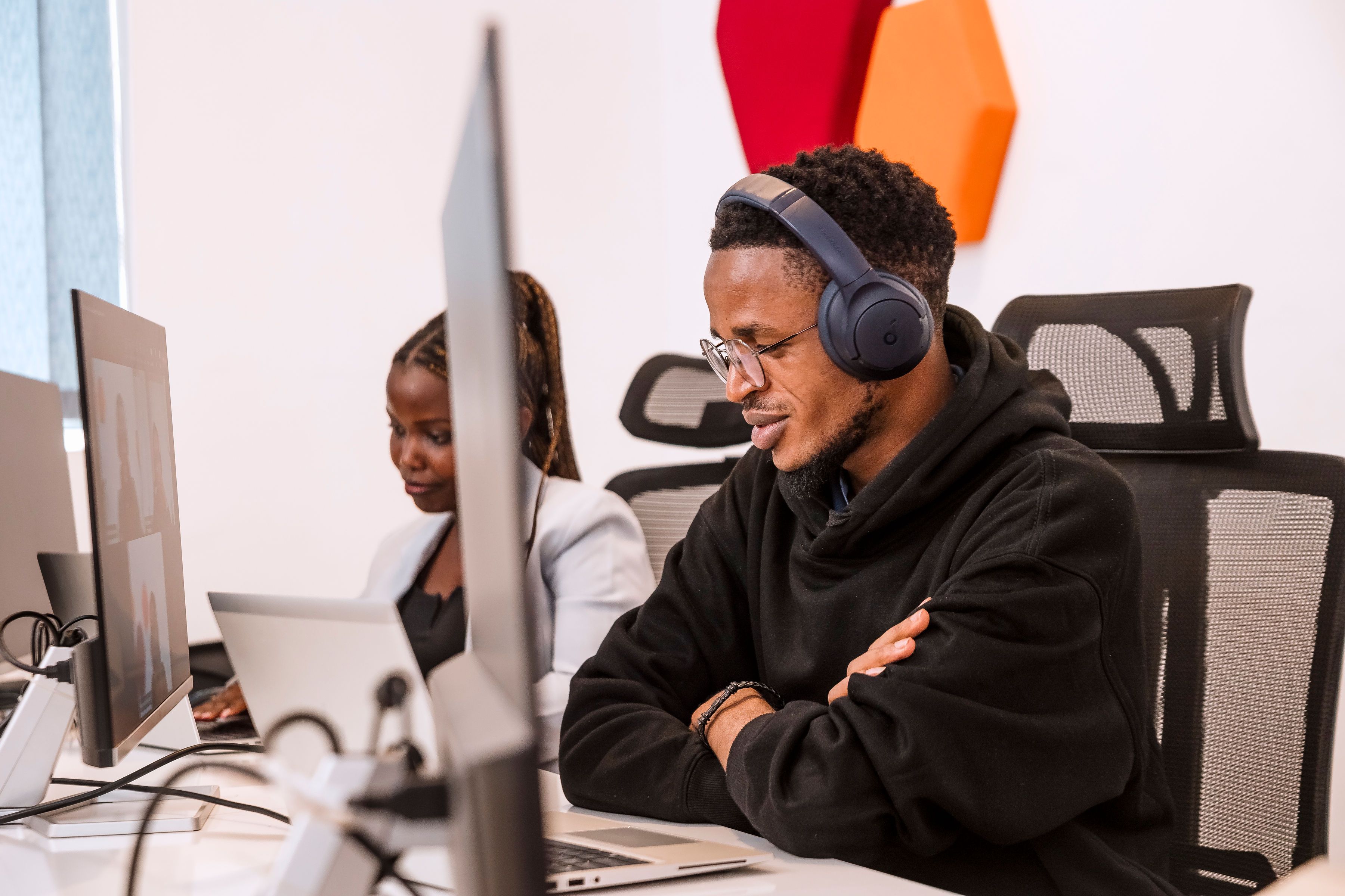 A man wearing headphones, sitting at his desk with a computer in front of him. 