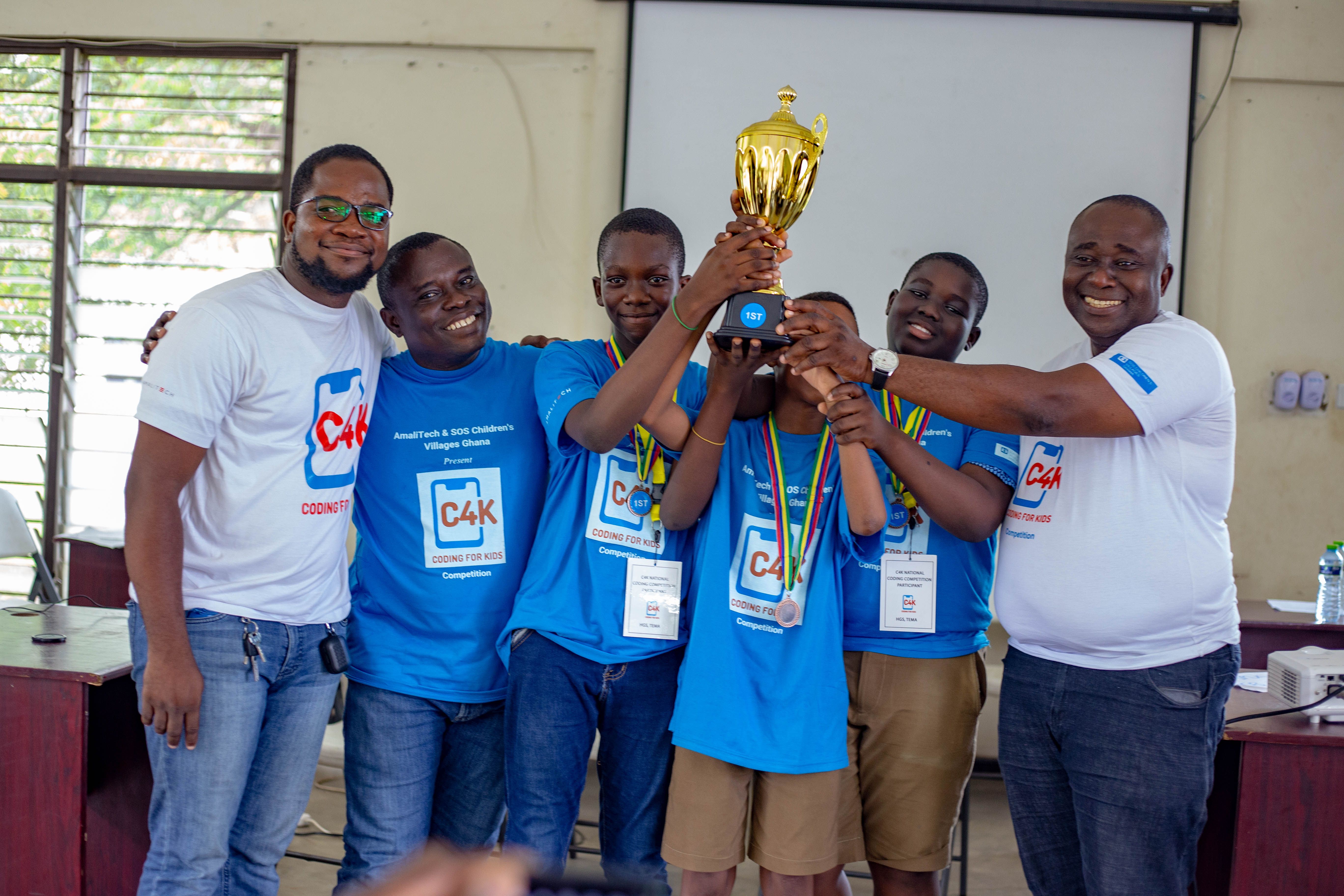 A group of childern and adults holding a trophy and smiling