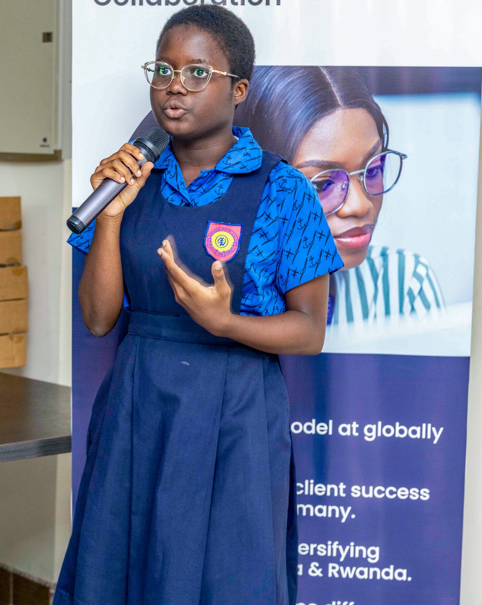 A girl wearing a blue dress and holding a microphone while she is talking