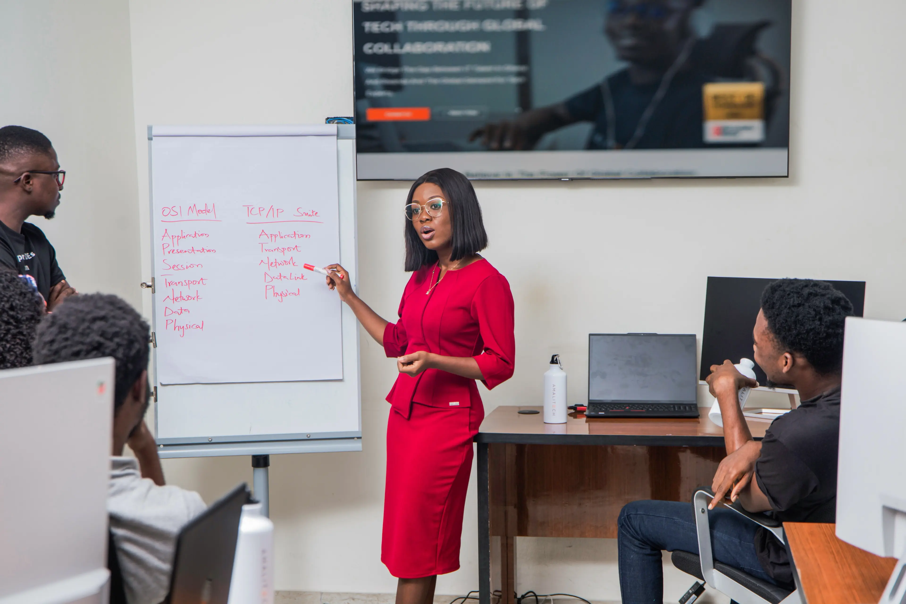 a young lady in front of a white board presenting to other people