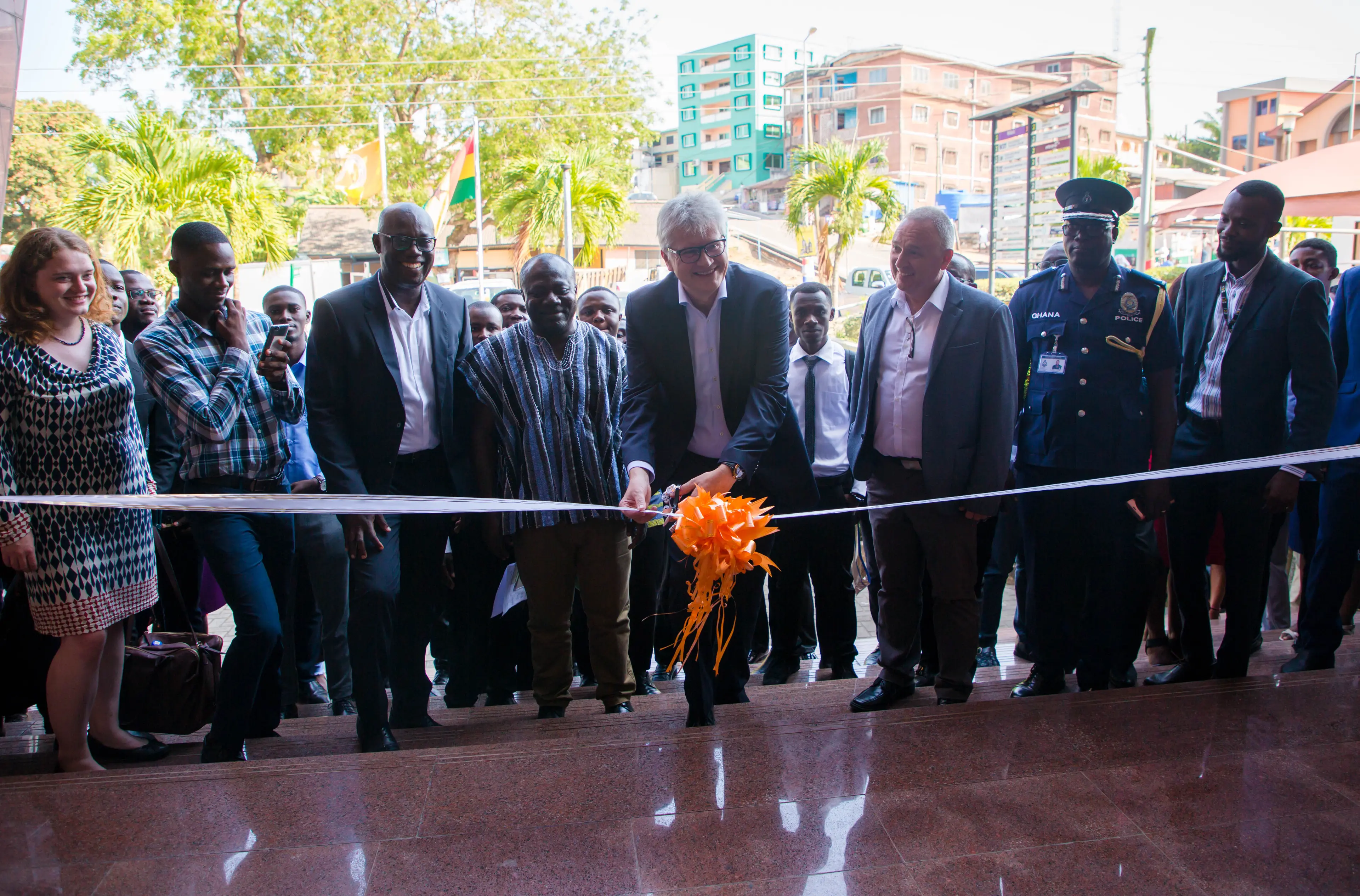 The CEO and Founder of AmaliTech, cutting the bow to the new office in Takoradi. There is a group of people standing next to him and behind him.
