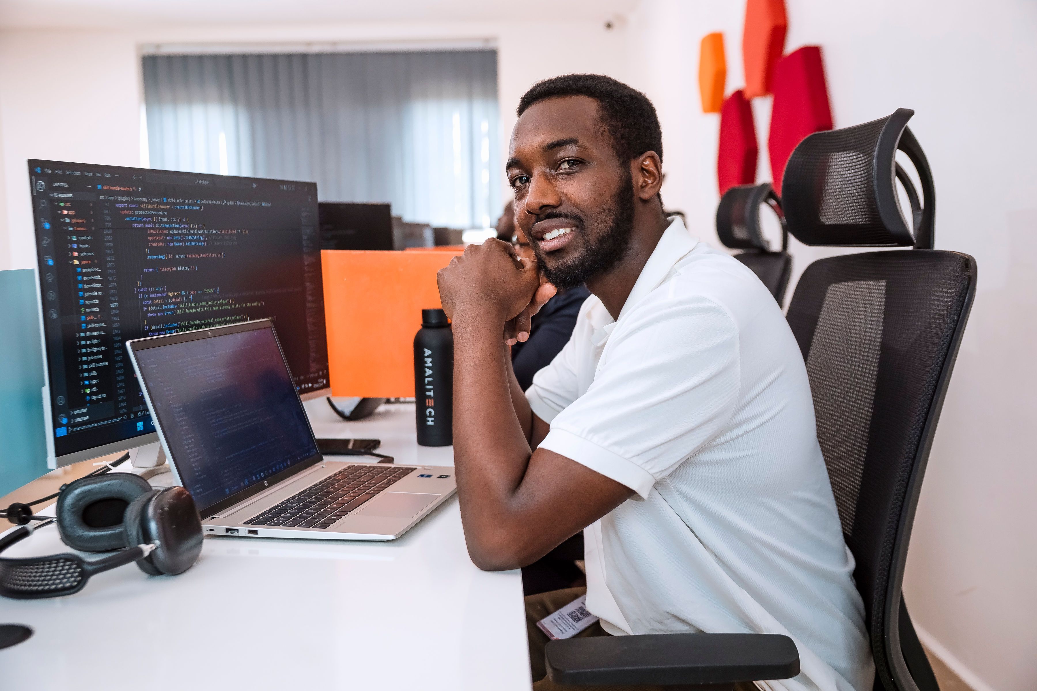 A man sitting at his desk with a laptop in front of him, facing the camera.