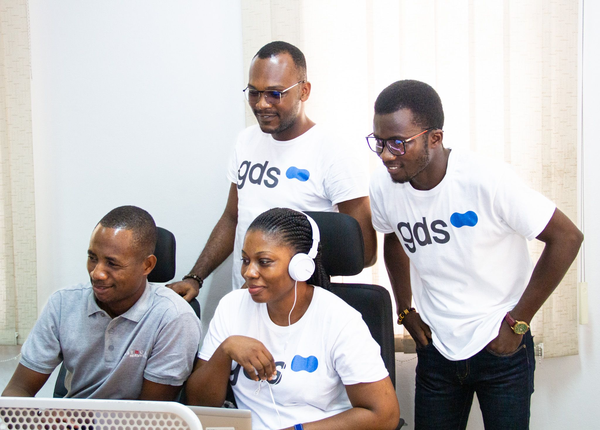 a team wearing gds tshirts, working on a computer, smiling.