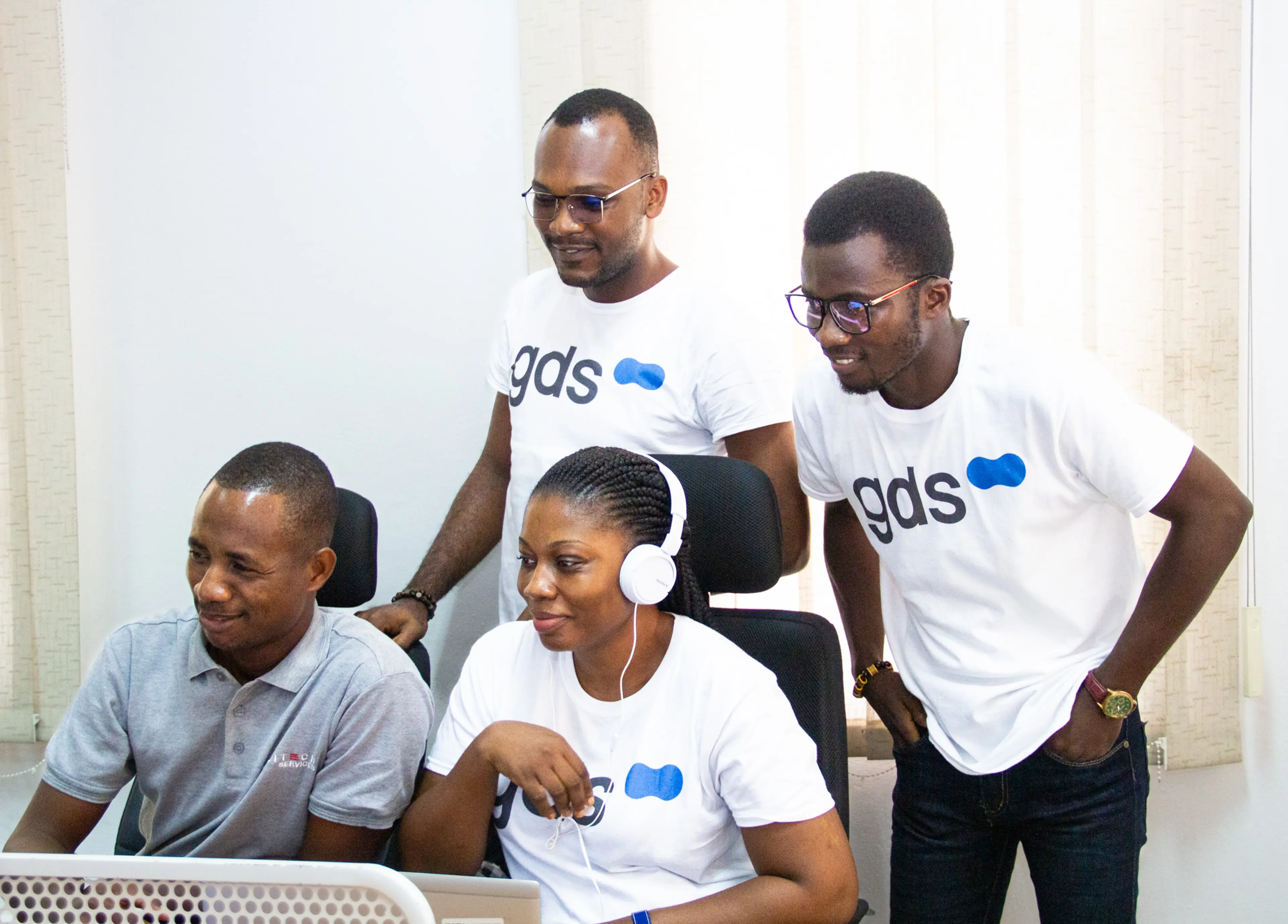 a team wearing gds tshirts, working on a computer, smiling.