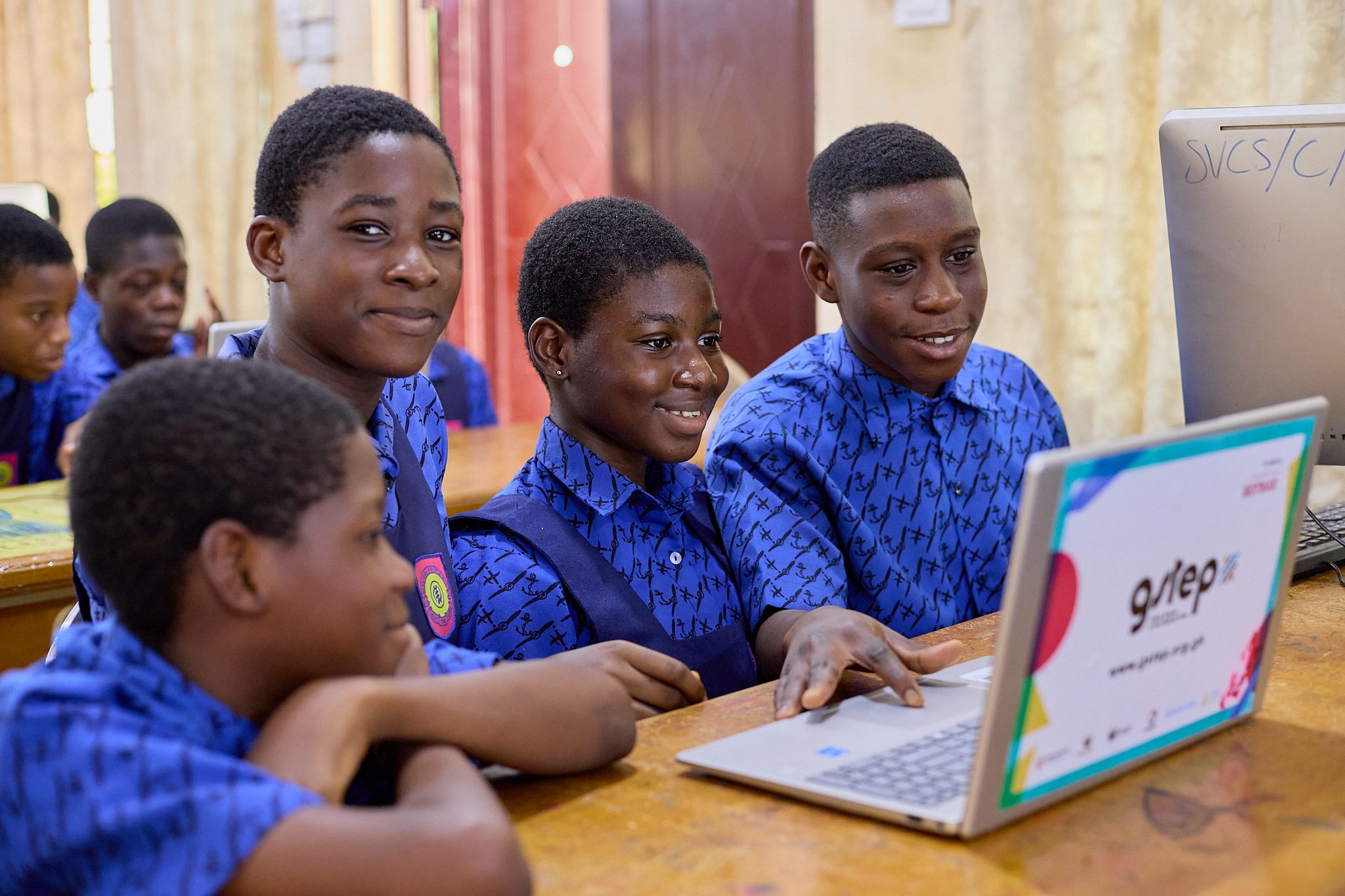 Four children working on a computer and laughing