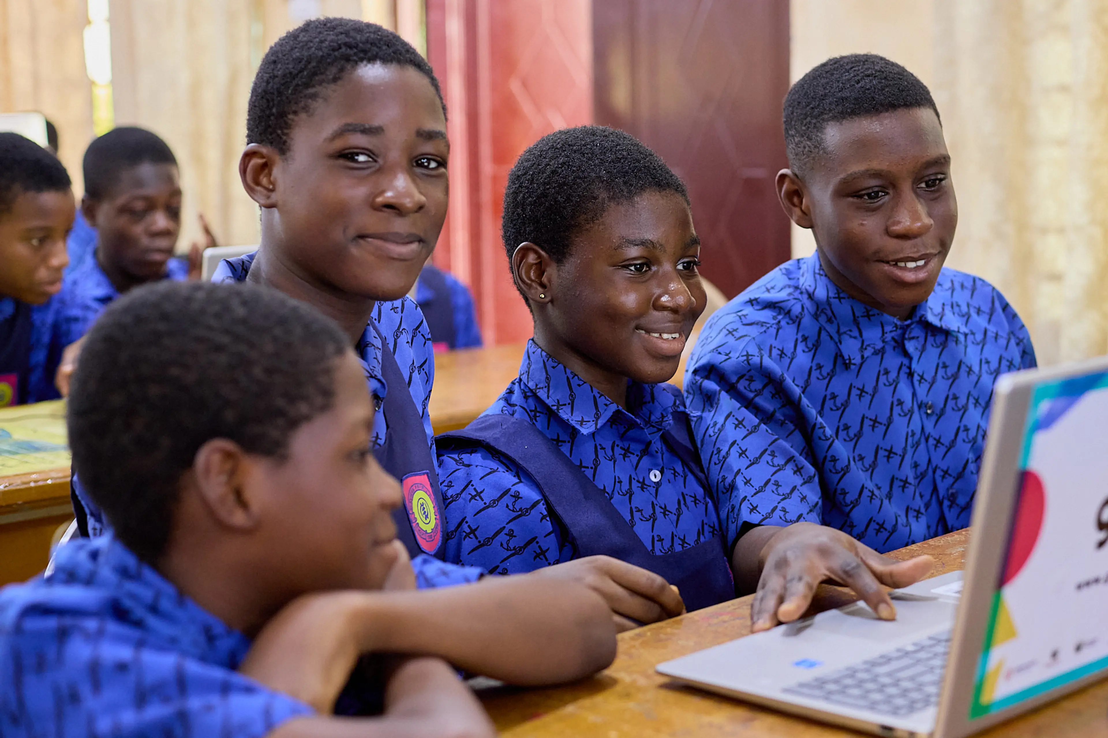 Four children working on a computer and laughing