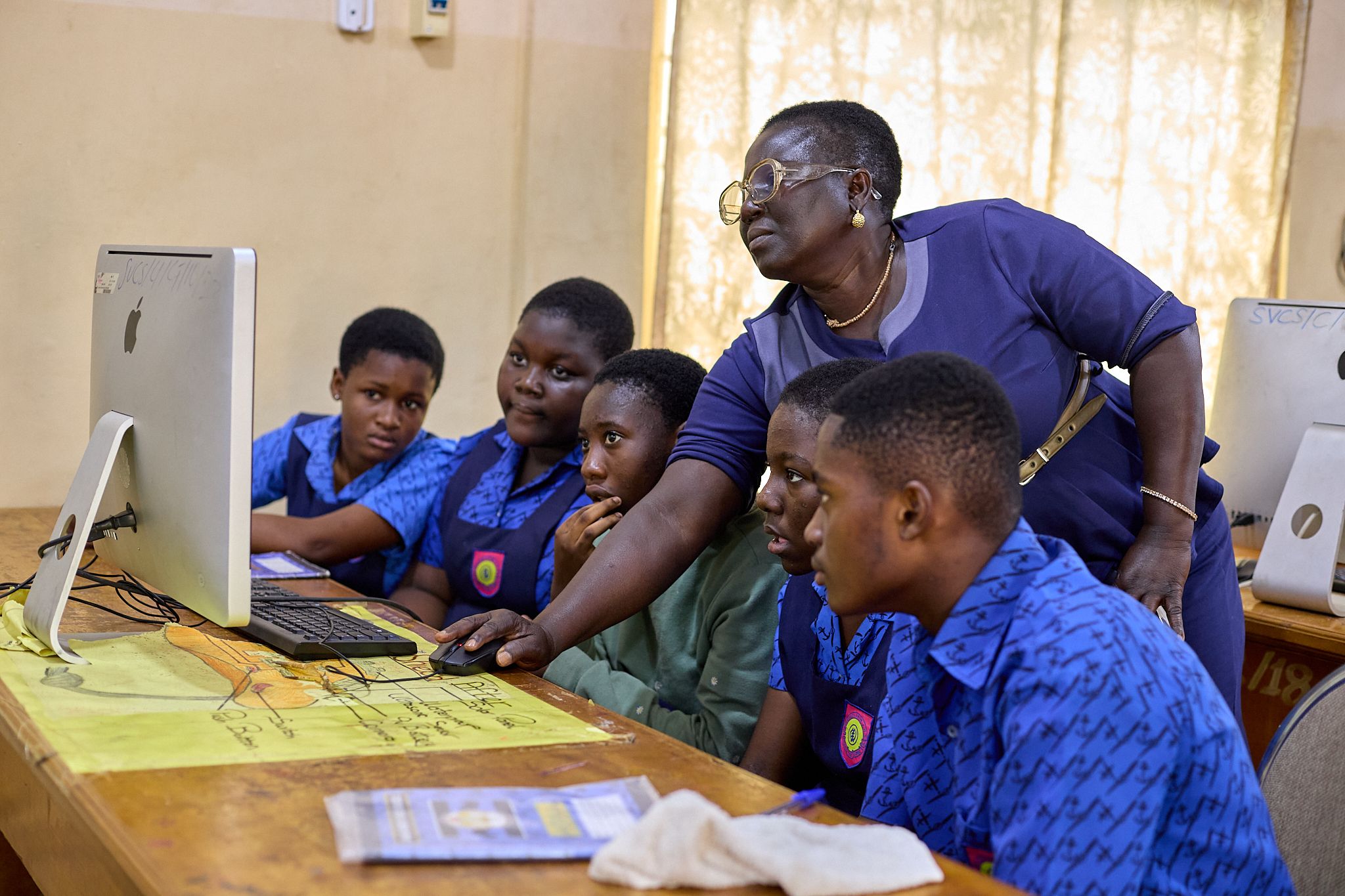 A mentor helping 5 children with their computer