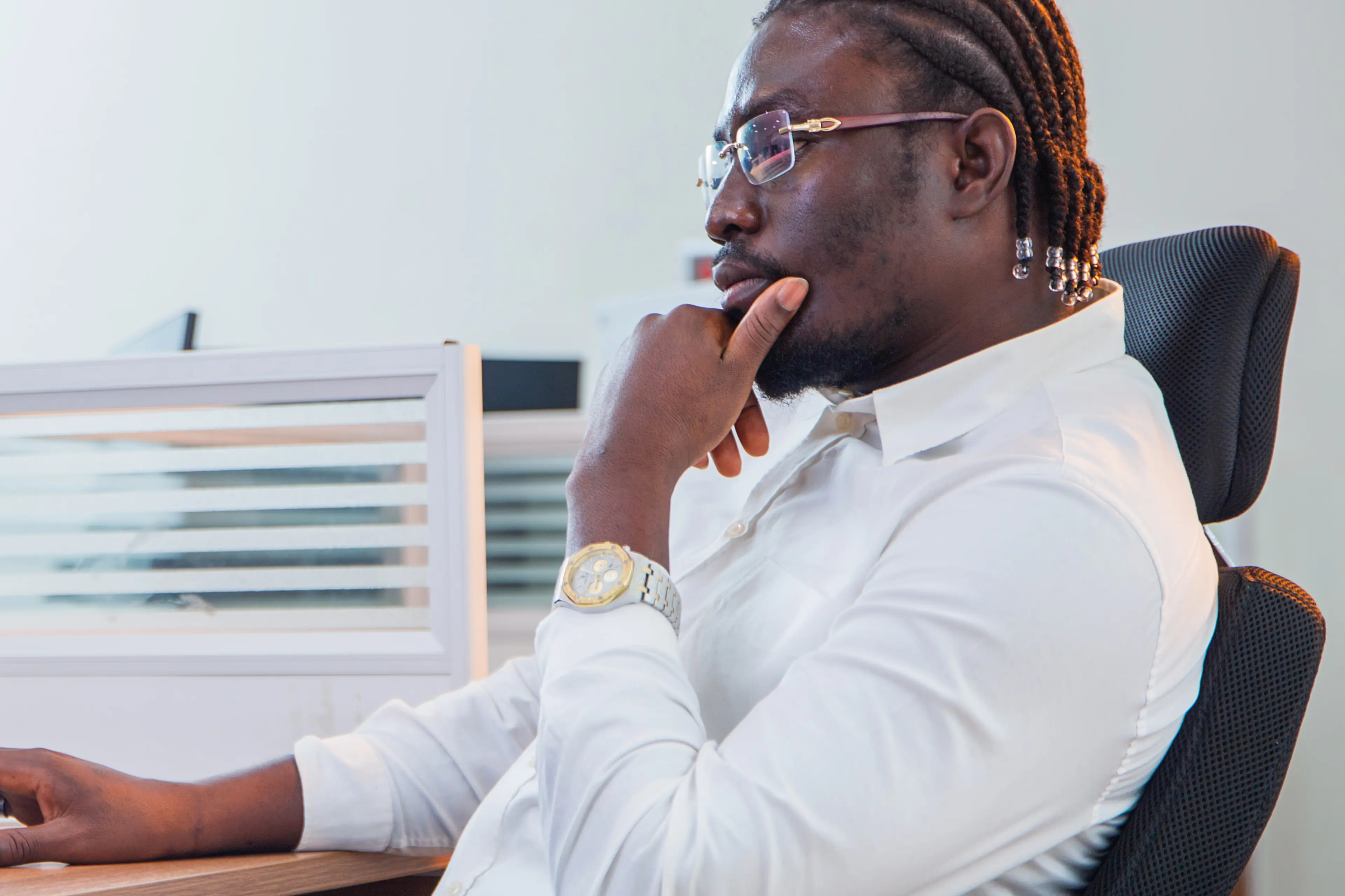 A man wearing a white shirt, working on his computer at his desk