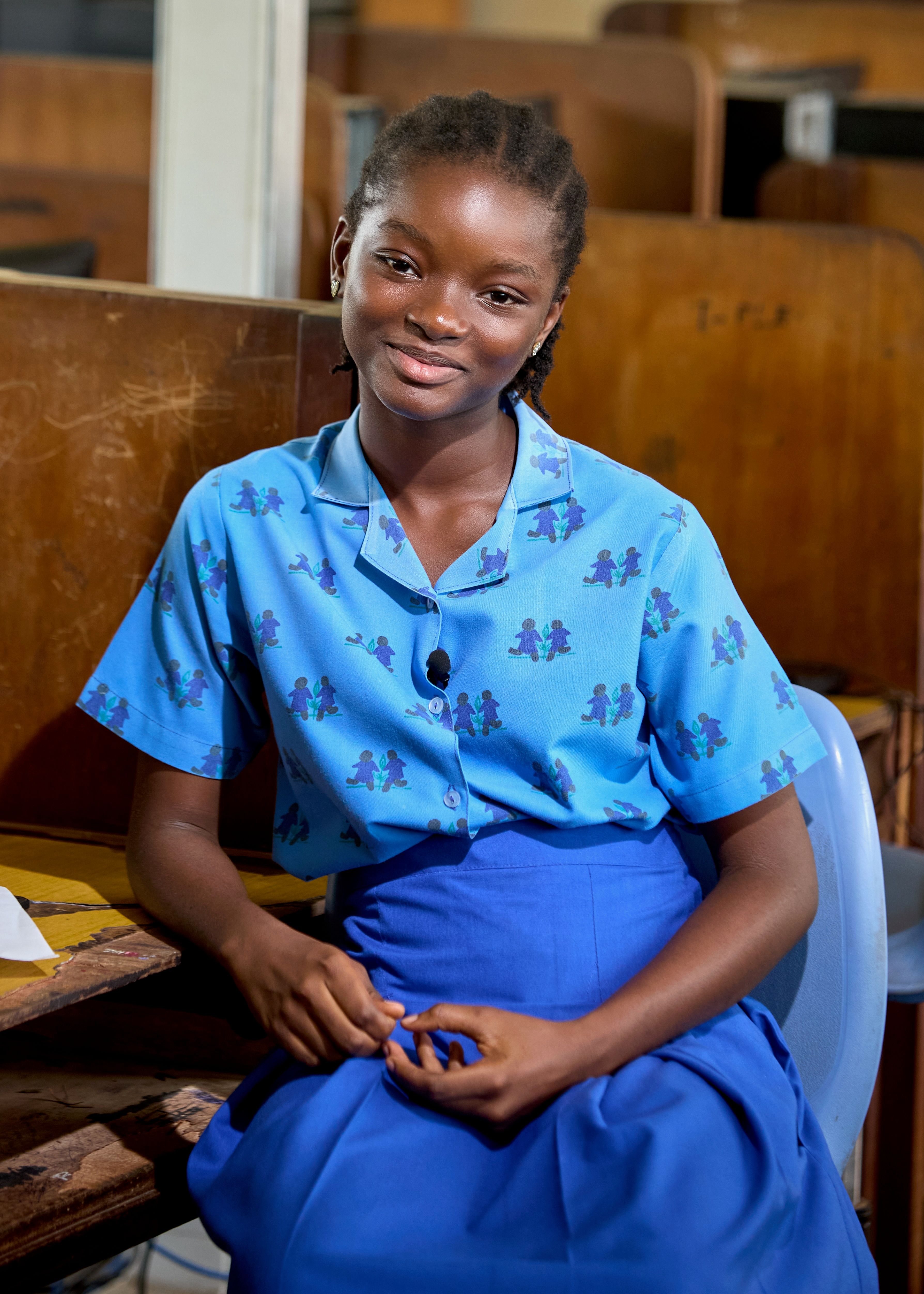 A girl wearing a blue uniform, smiling at the camera