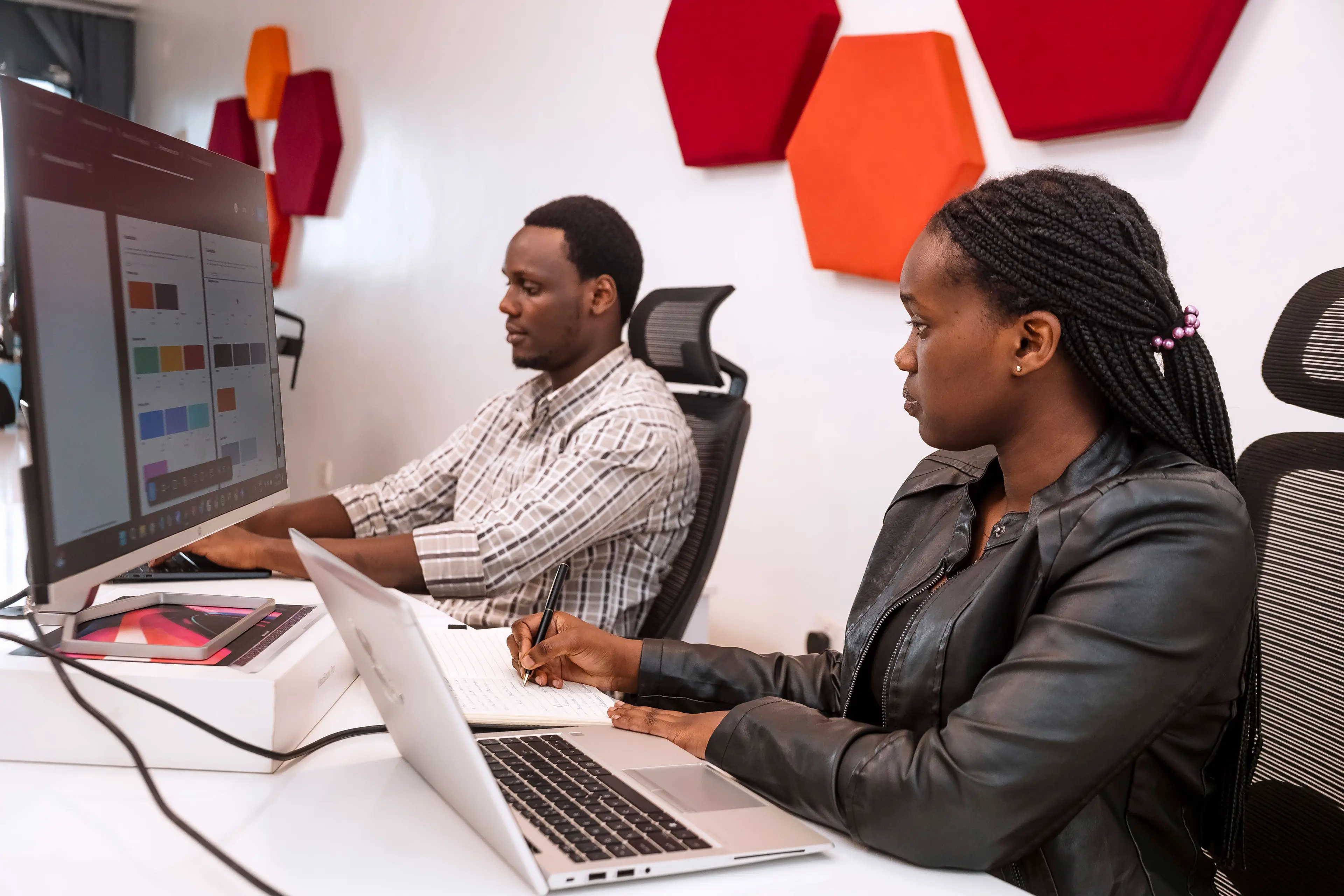 two people working at their desks, on their computers.
