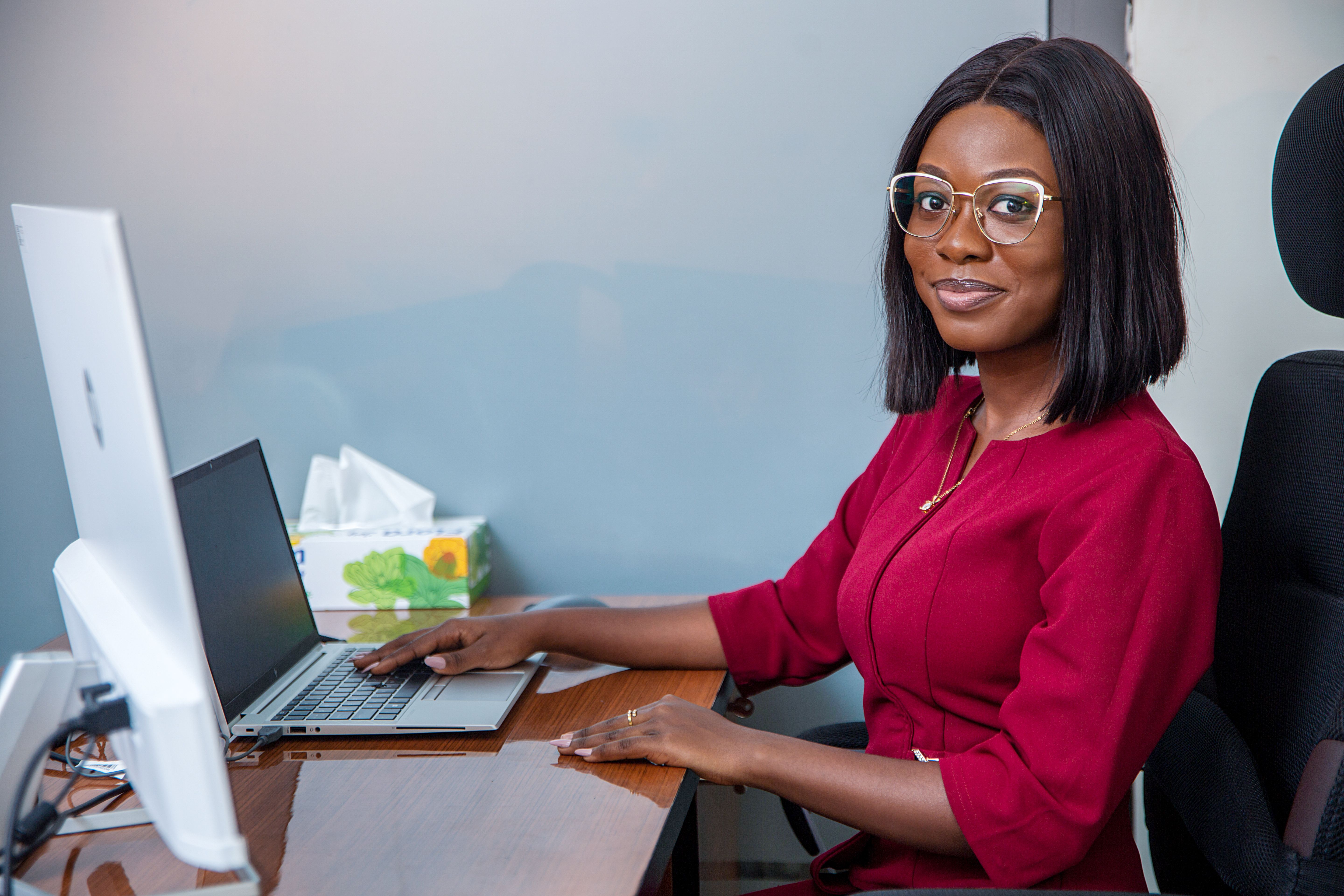 A young lady seated behind a desktop and smiling at the camera