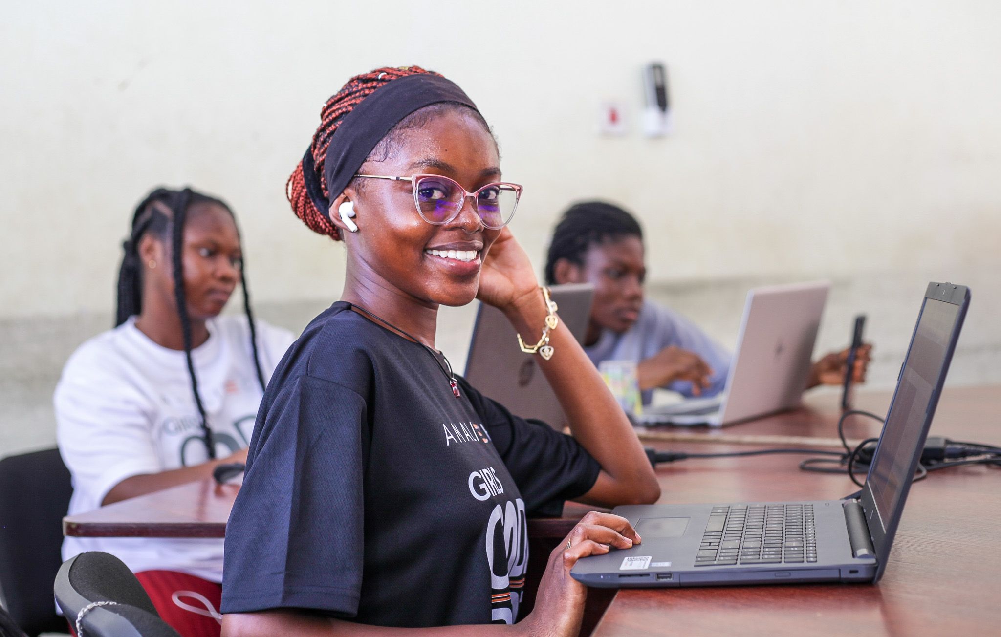 A women sitting in front of the computer, facing right and smiling at the camera