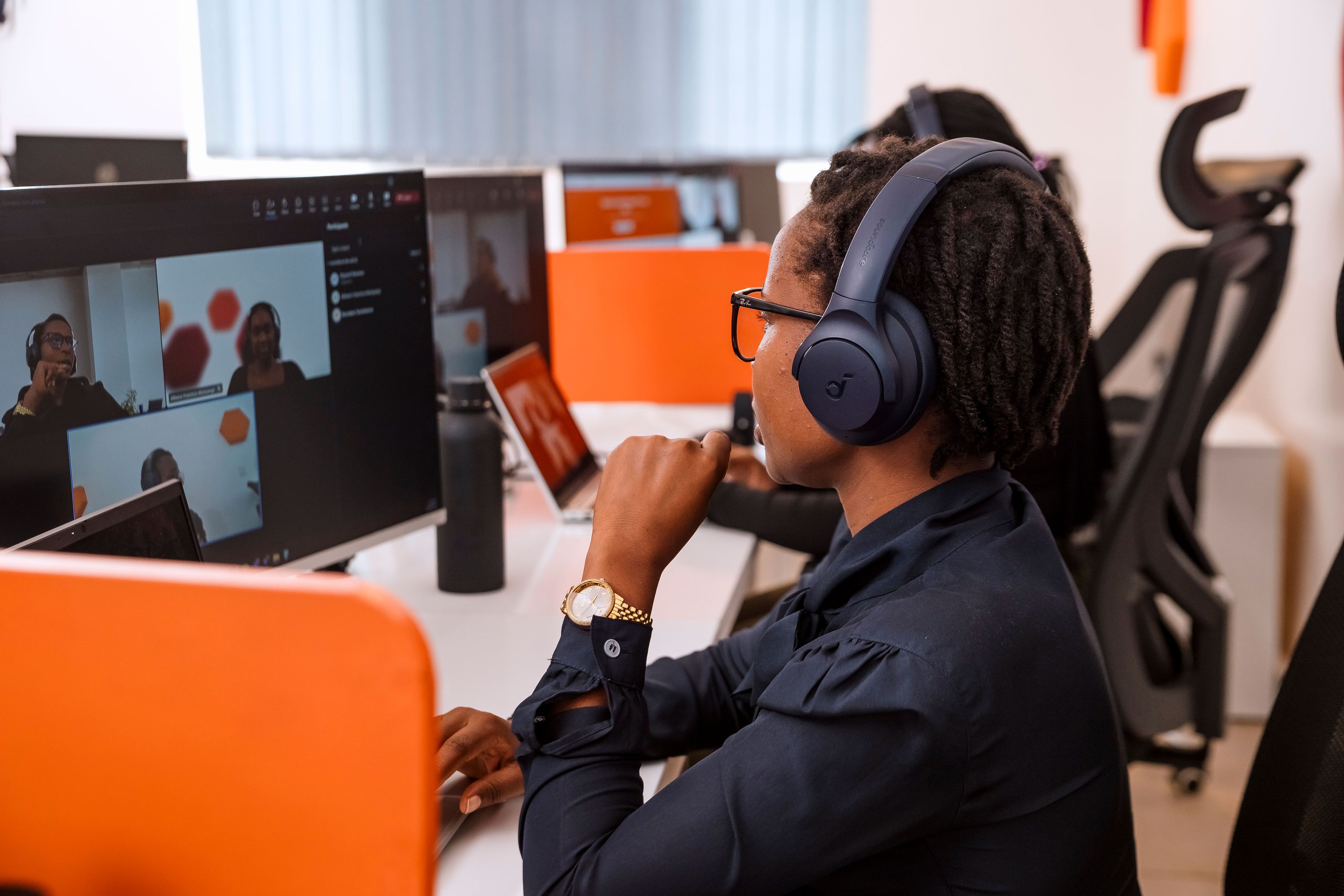 A women taking part in a virtual meeting. She is sitting at her desk and wearing headphones.