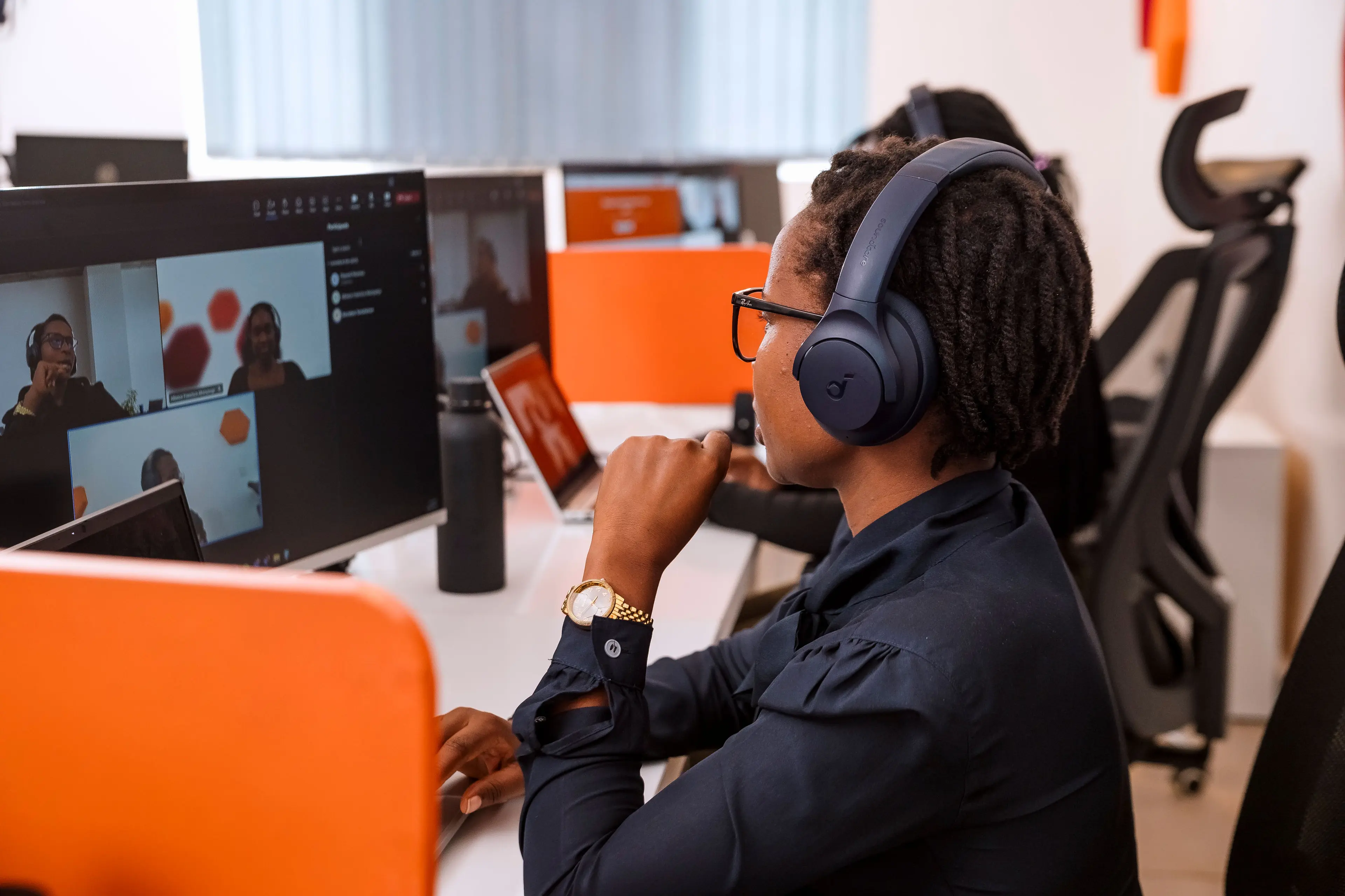 A women taking part in a virtual meeting. She is sitting at her desk and wearing headphones.