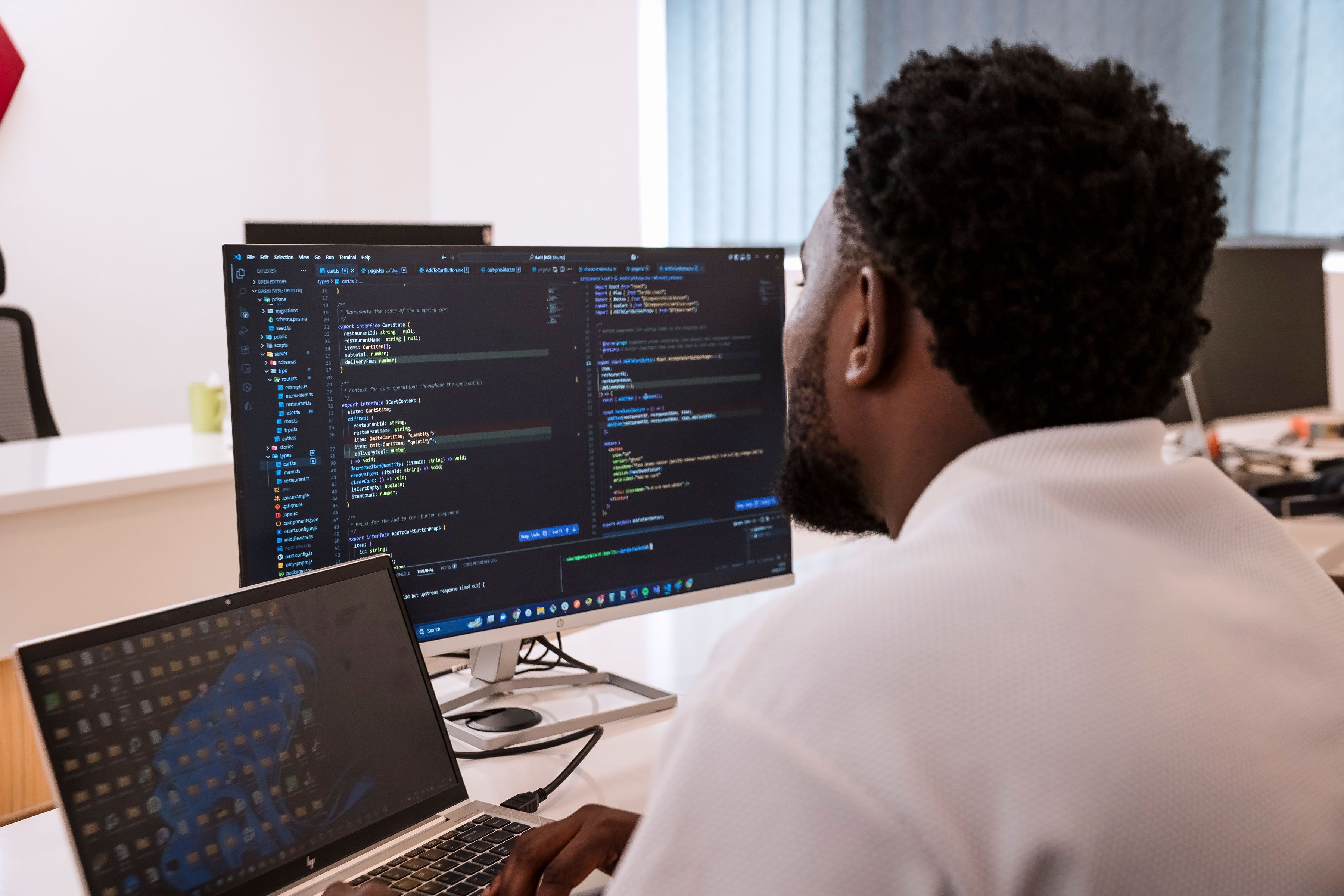A guy behind the laptop looking at the screen with codes on