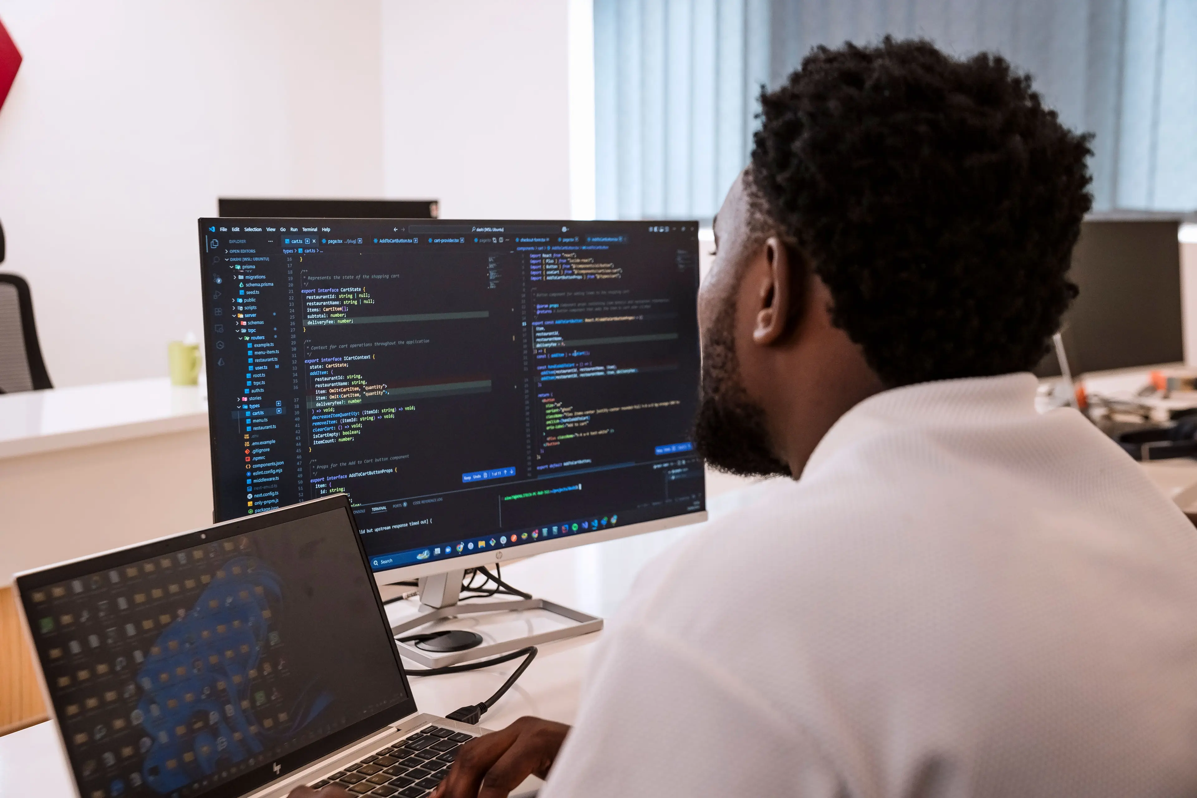 A guy behind the laptop looking at the screen with codes on