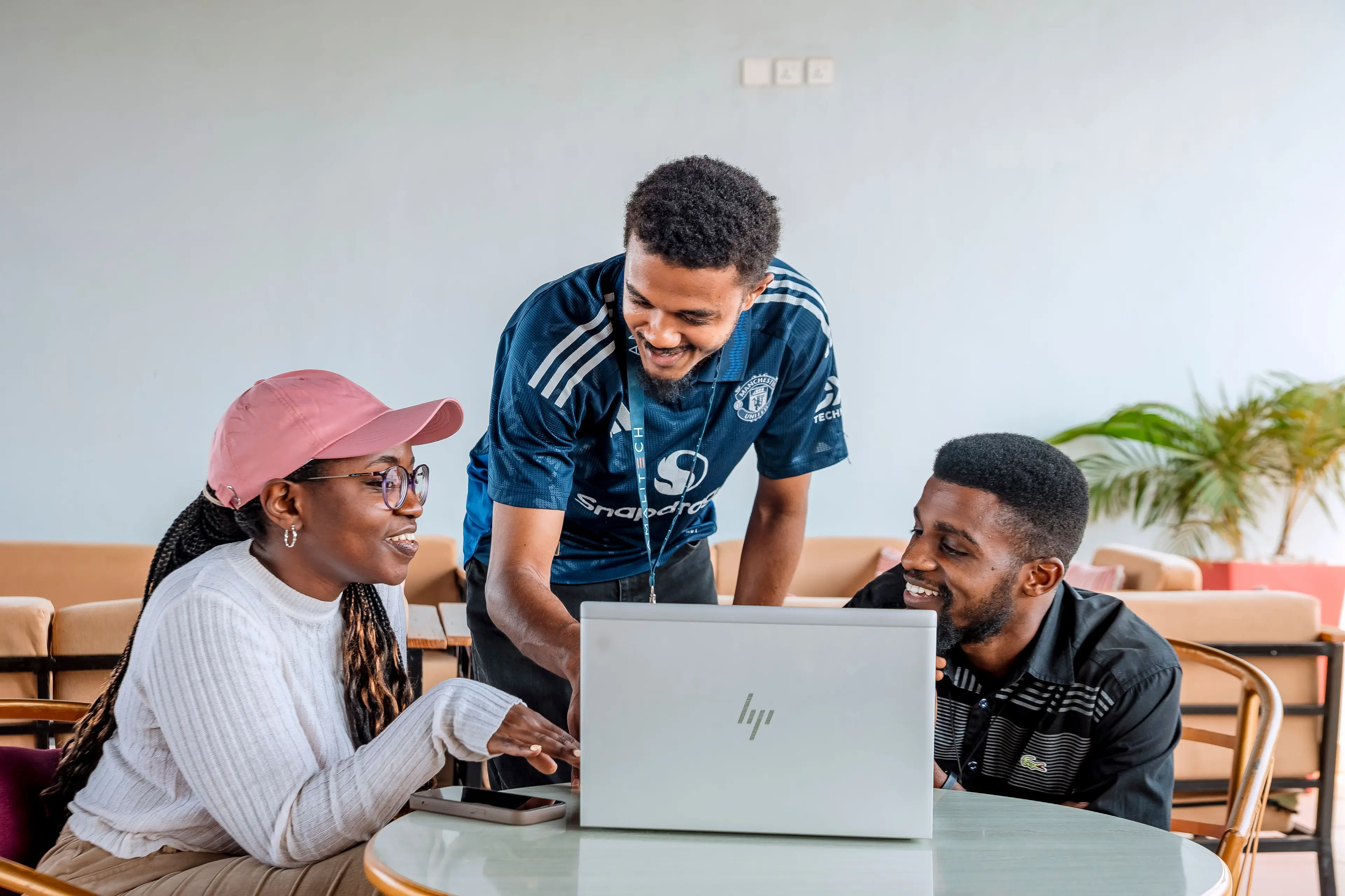 Two men and a women in conversation, with a laptop on a table