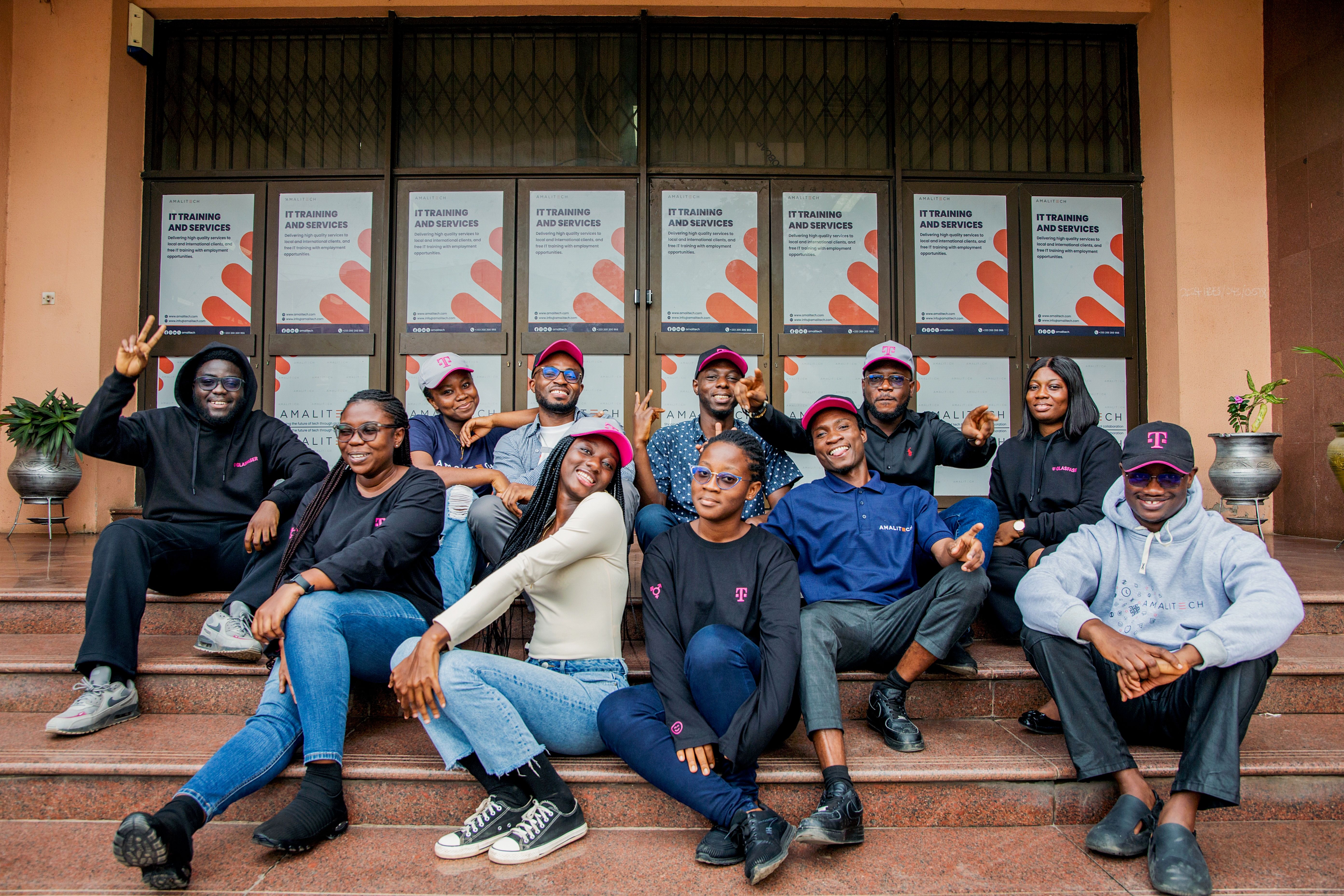A team sitting on a staircase, wearing Telekom hats and smiling at the camera