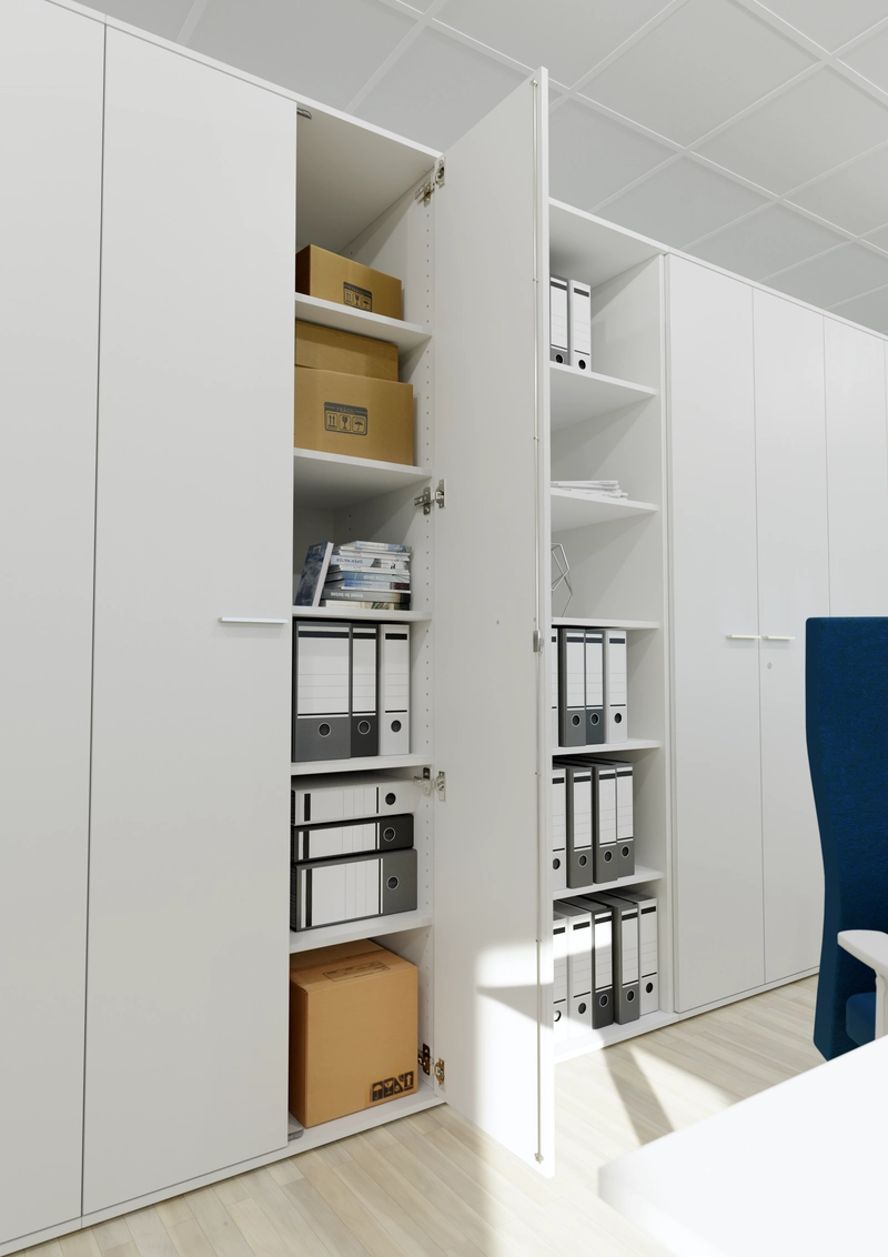 Geöffneter weißer Flügeltürenschrank mit Fachböden voller Ordner und Kartons, daneben ein offenes Regal.