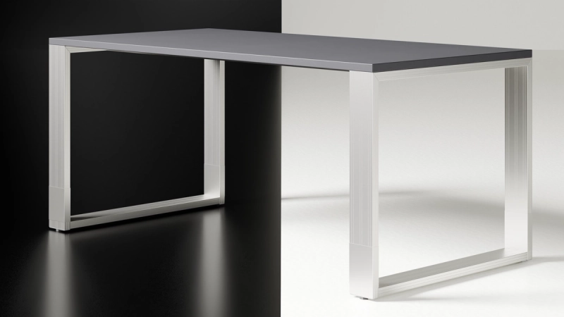 Freigestellter Quandos Schreibtisch mit anthrazitfarbener Platte auf zwei offenen Aluminiumrahmen.