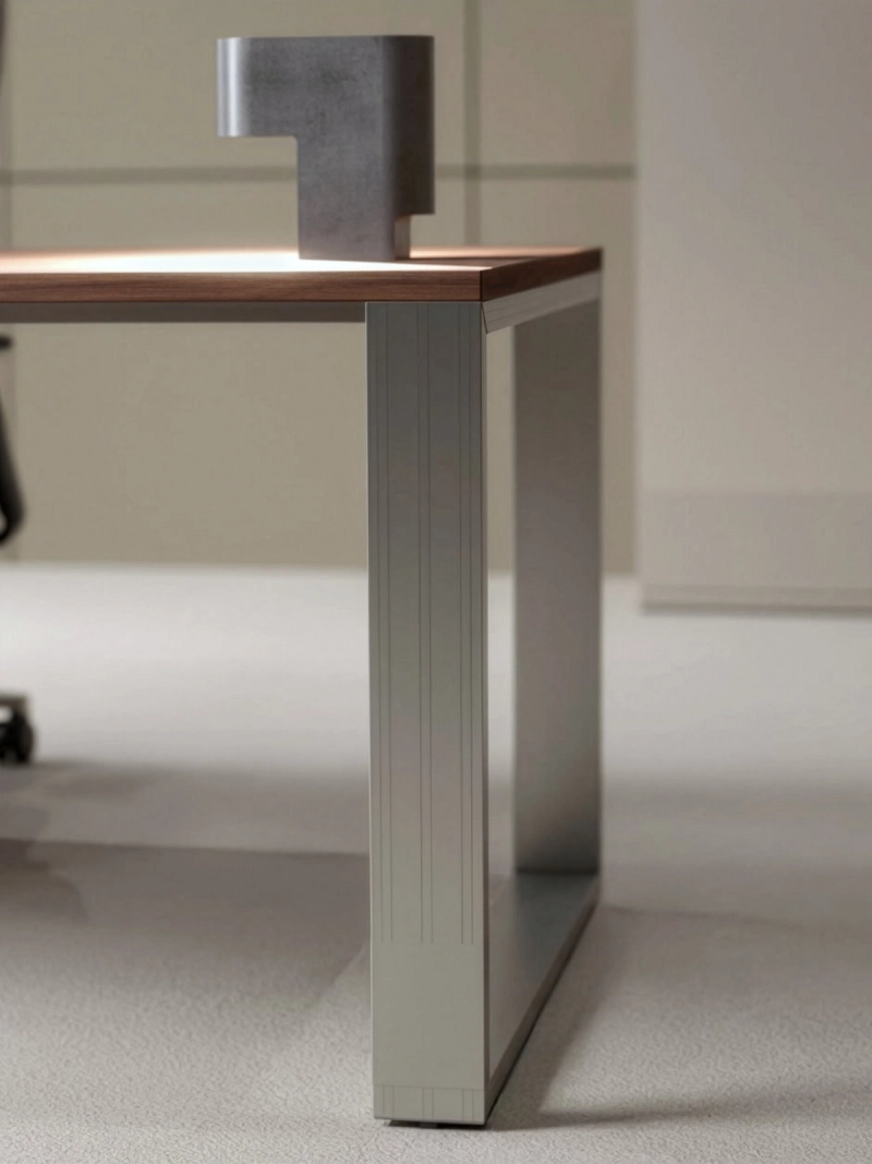 Quandosschreibtisch in Seitenansicht mit elegantem Aluminiumgestell, robuster Konstruktion und hochwertiger Tischplatte in einem modernen minimalistischen Einzelbüro mit beigen Farbtönen.