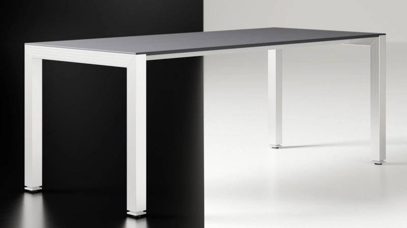 Freigestellter Solus Schreibtisch mit anthrazitfarbener Platte auf weißem Aluminiumrahmen.