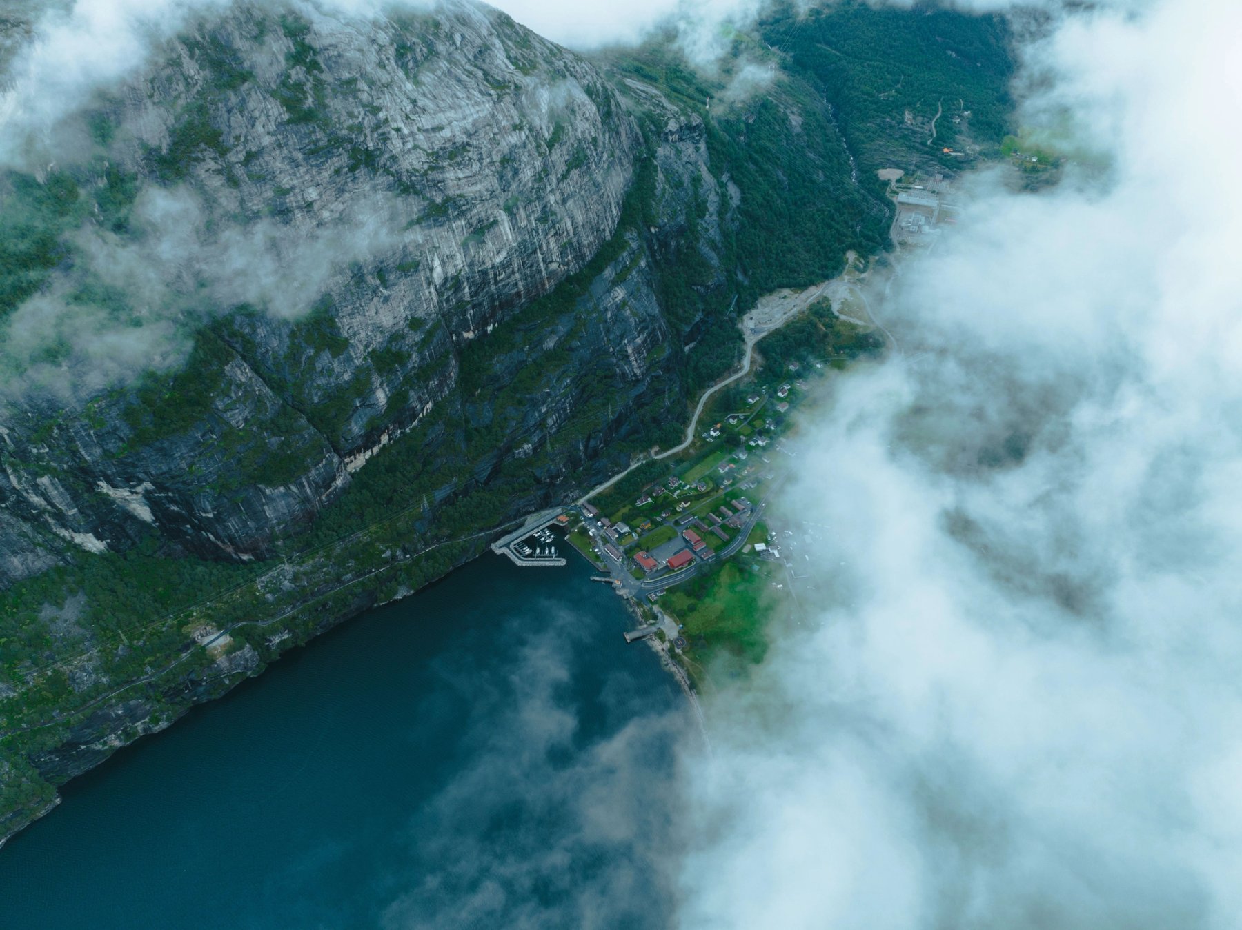 Aerial view of Norwegian fjord village surrounded by mountains and fog