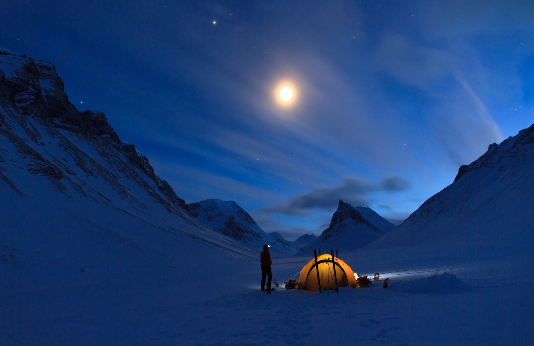 orange tent in winter landscape with high mountains around