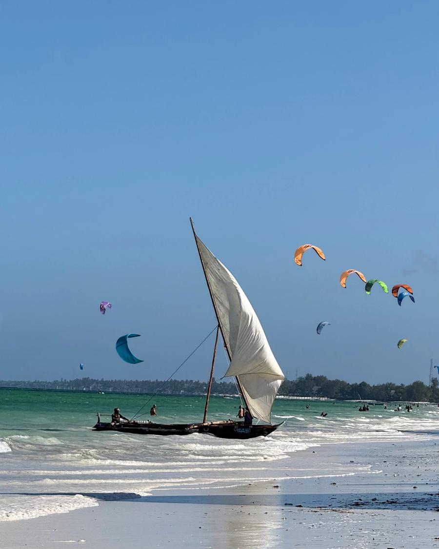 Vela de dhow com kitesurfistas ao fundo, em Paje.