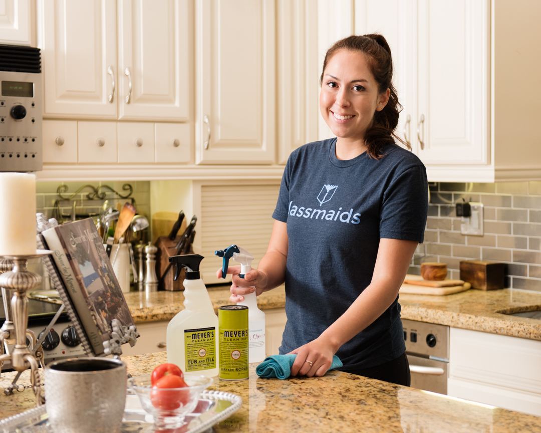 A smiling Classmaids cleaner wiping a granite kitchen counter
