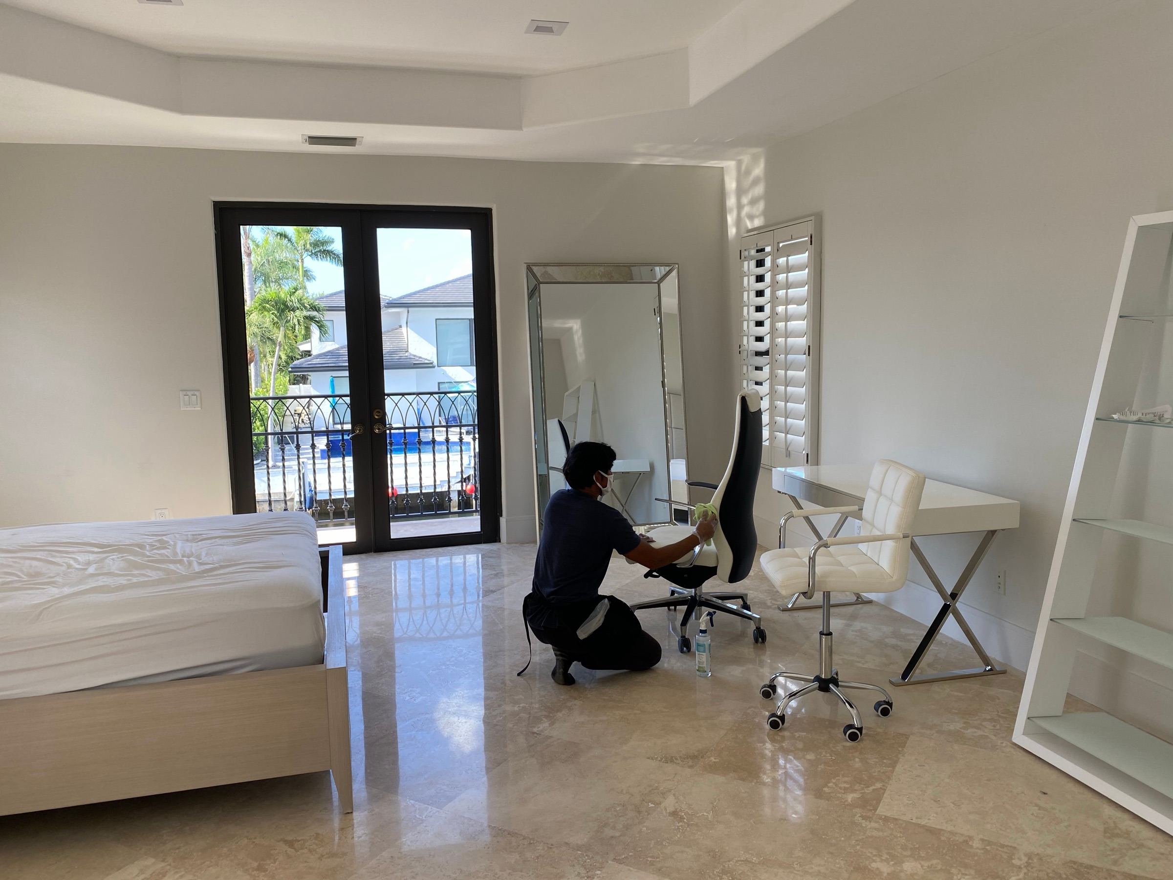 A Classmaids cleaner detailing a desk chair in a sparsely furnished bedroom with a bare mattress