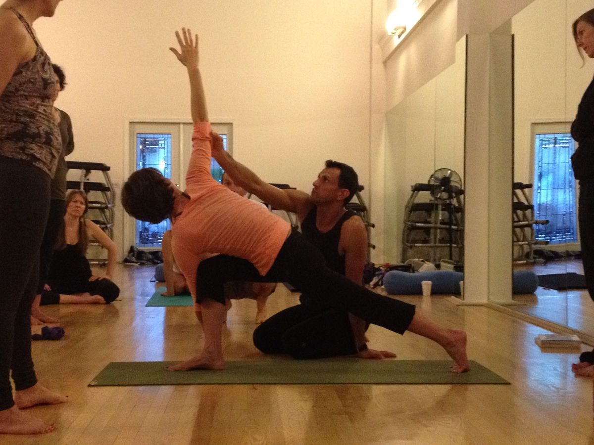 Doron giving a hands-on assist in a seated pose.